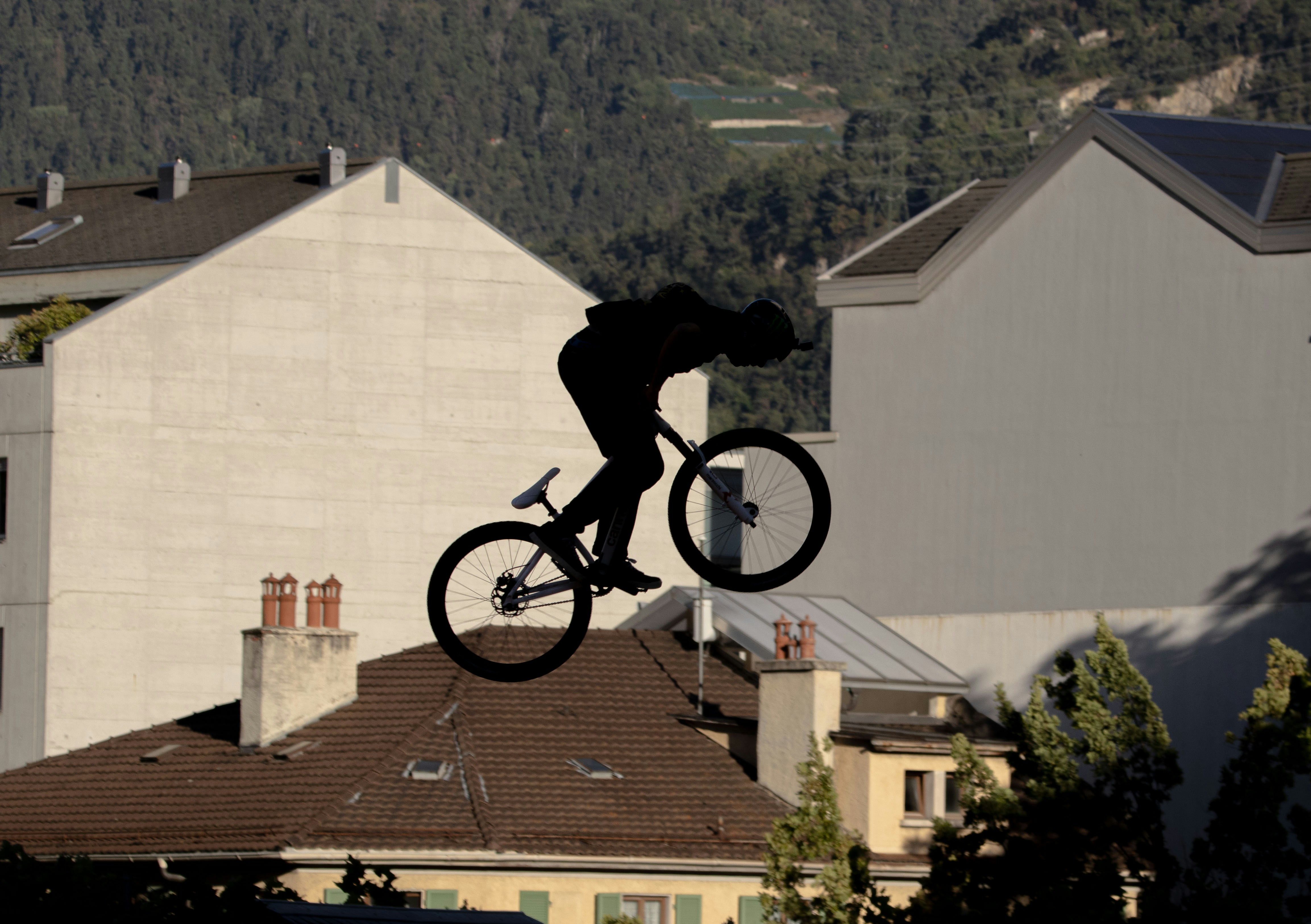 Silhouette of a cyclist performing a jump over buildings.