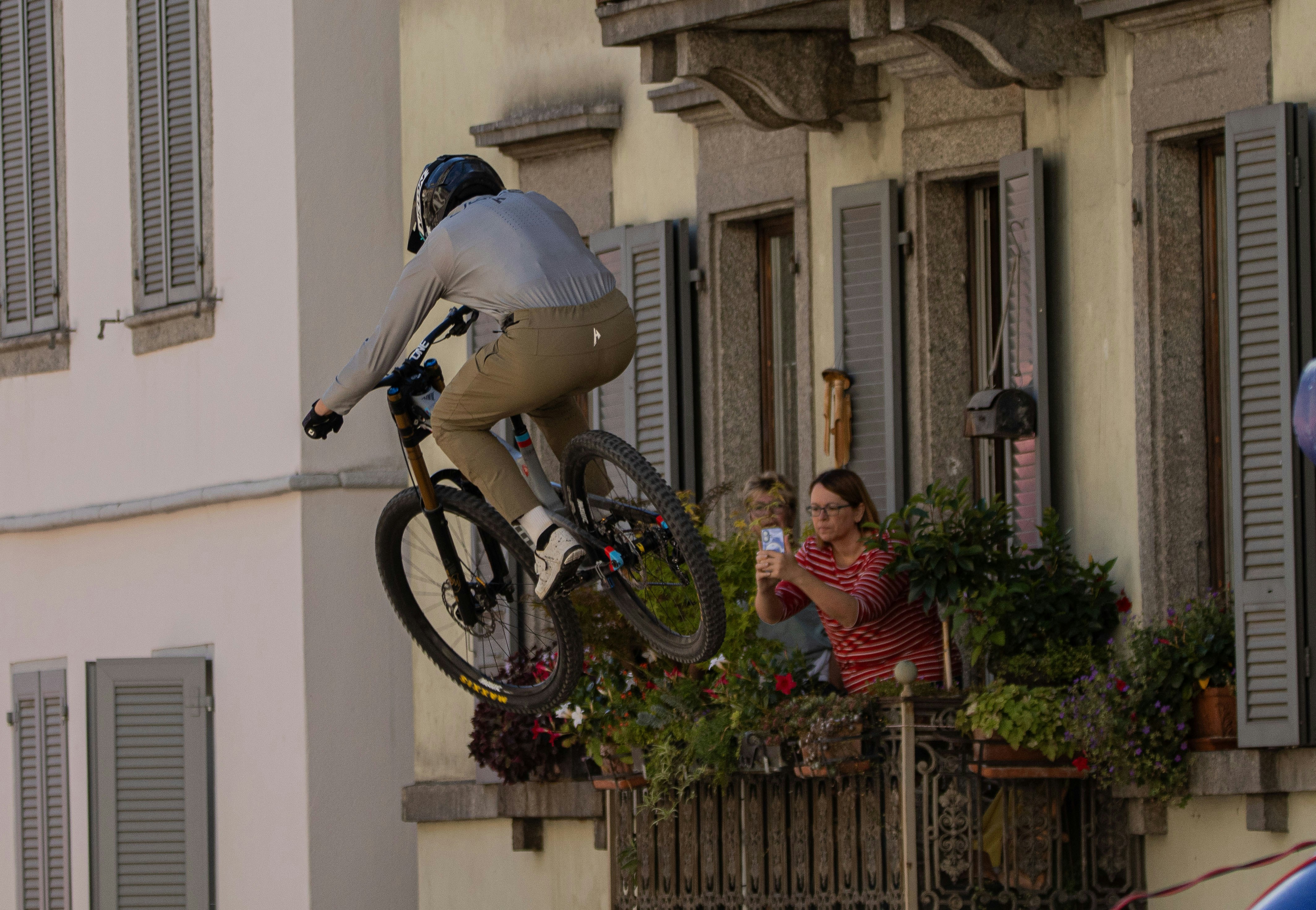 Cyclist performs stunt near balcony with onlookers