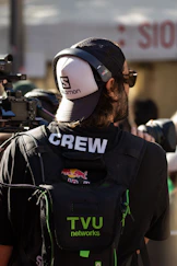 A cameraman wearing a hat and headphones with headphones