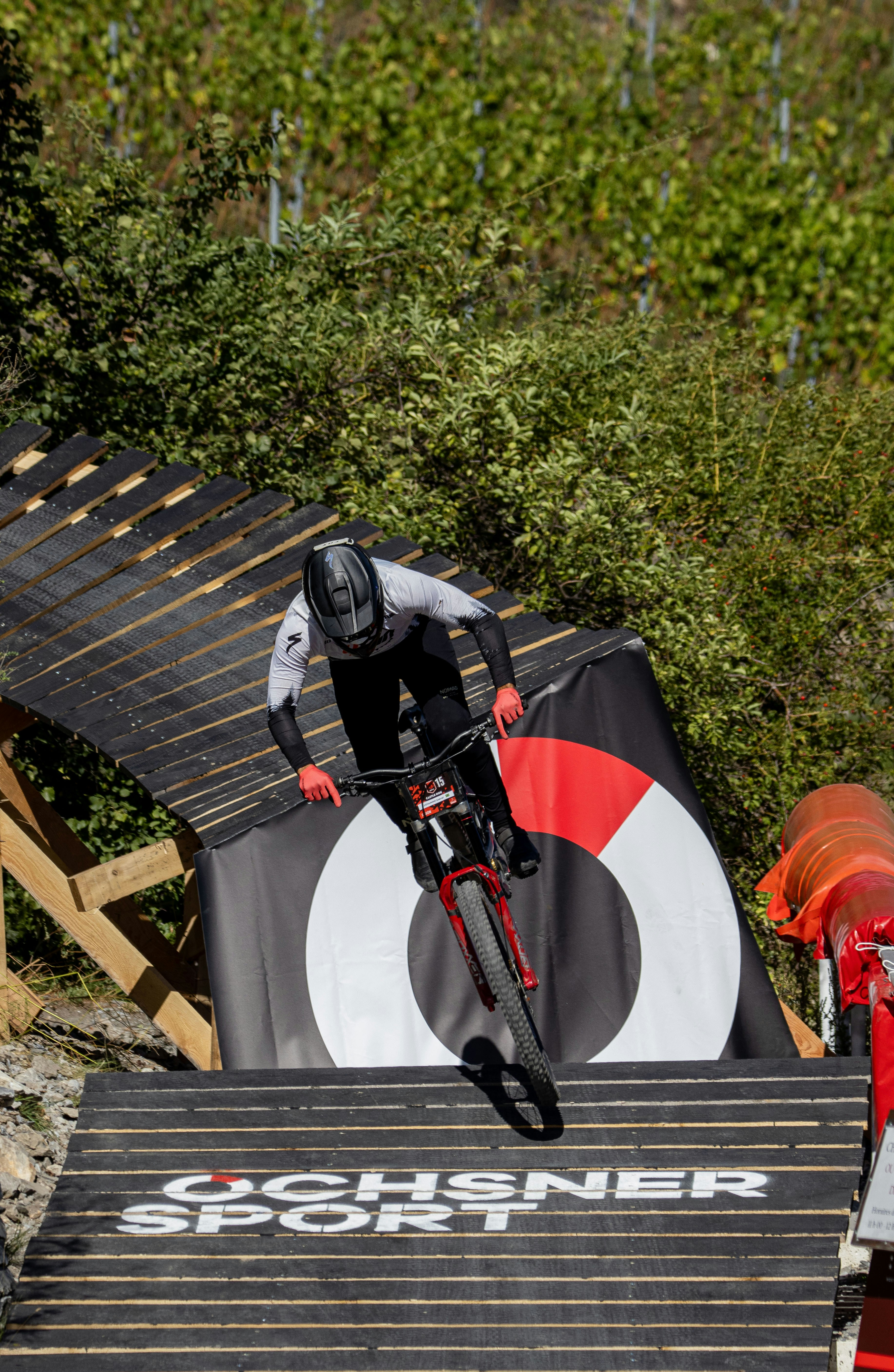 Mountain biker descends a ramp with a logo