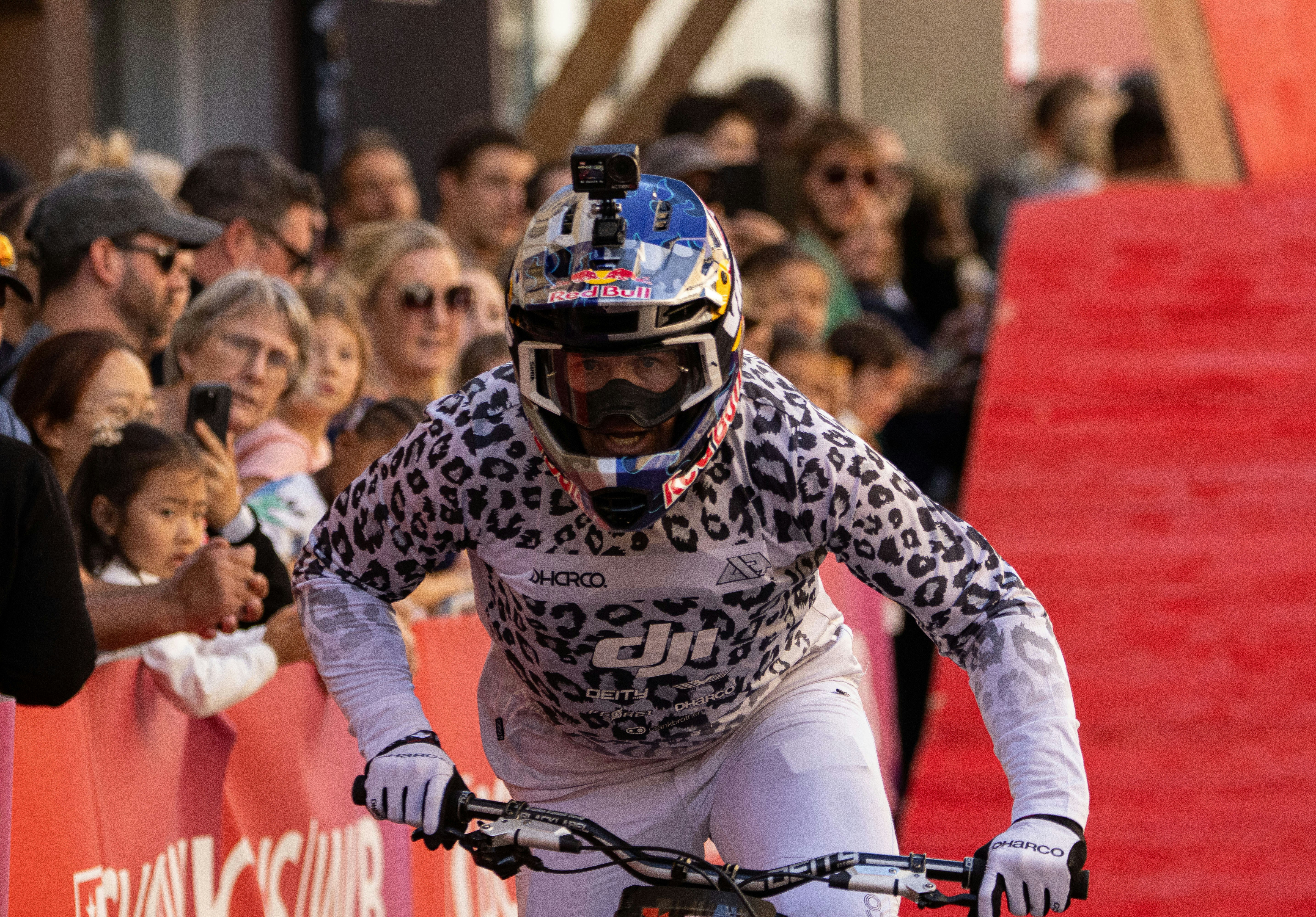 Mountain biker in leopard print gear races past spectators
