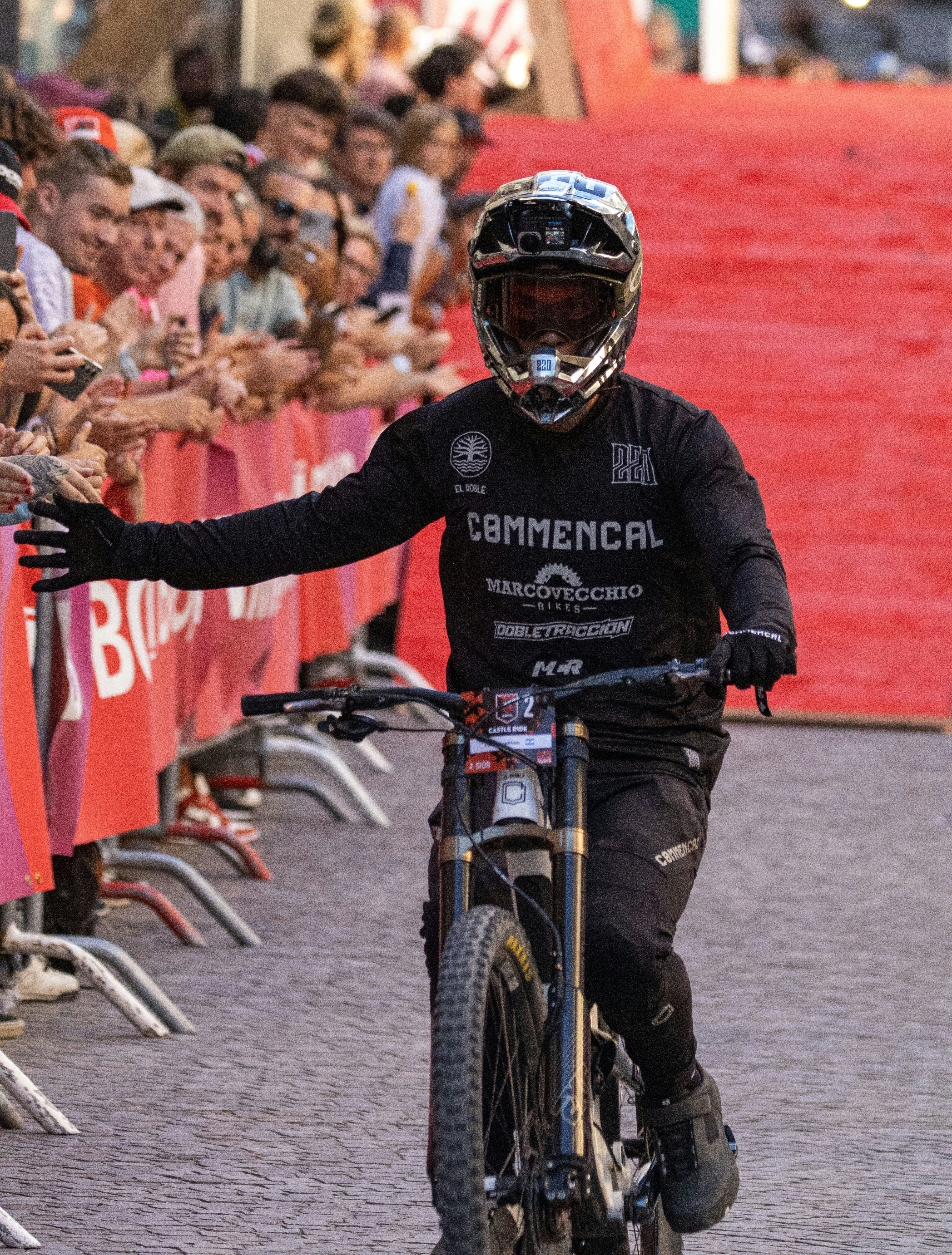 Cyclist in helmet waves to crowd after race