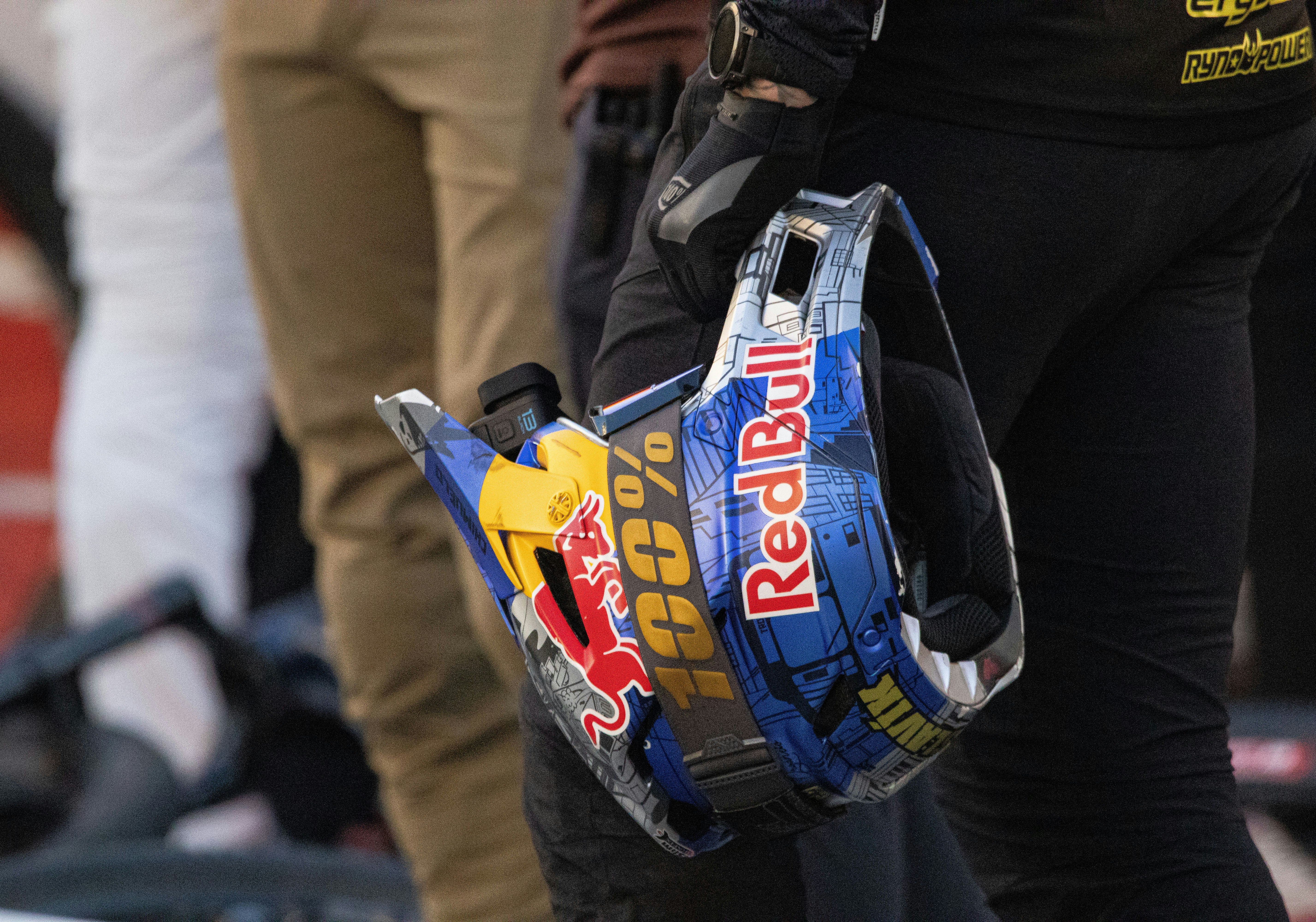 Rider holds red bull branded helmet with 100% logo.