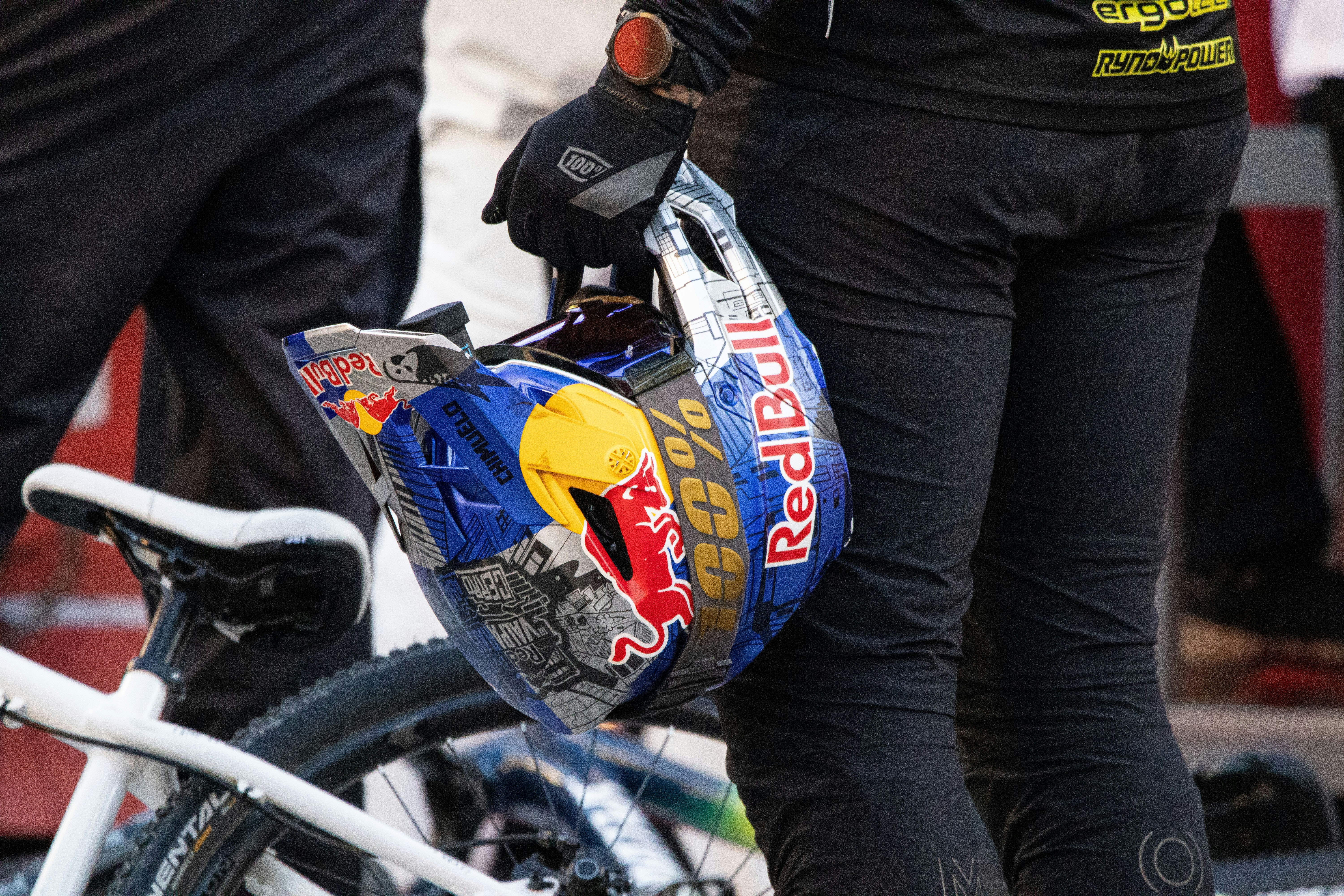 Person holding a red bull helmet with a bicycle.