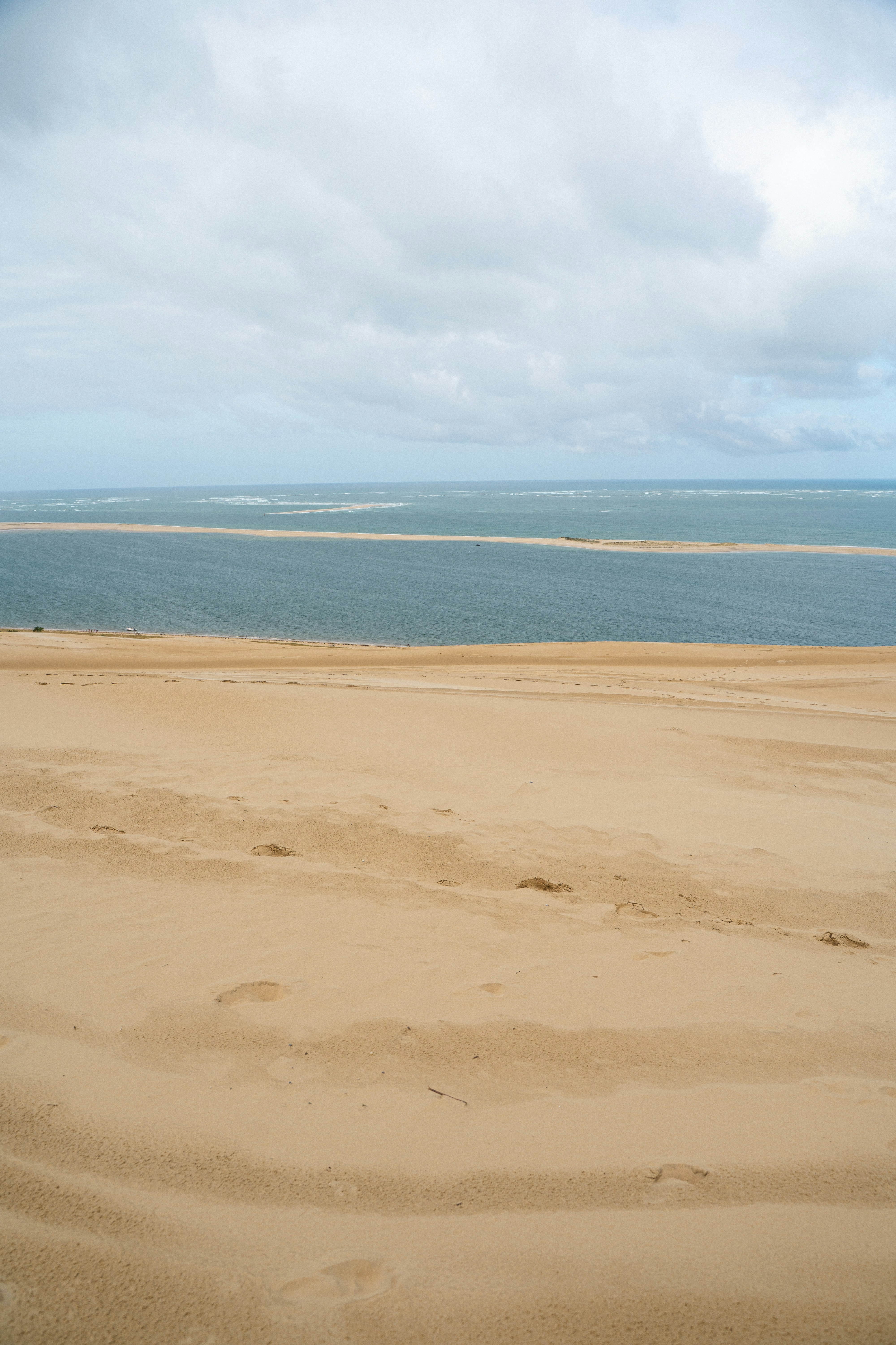 Las dunas de arena se encuentran con el océano en calma bajo cielos nublados