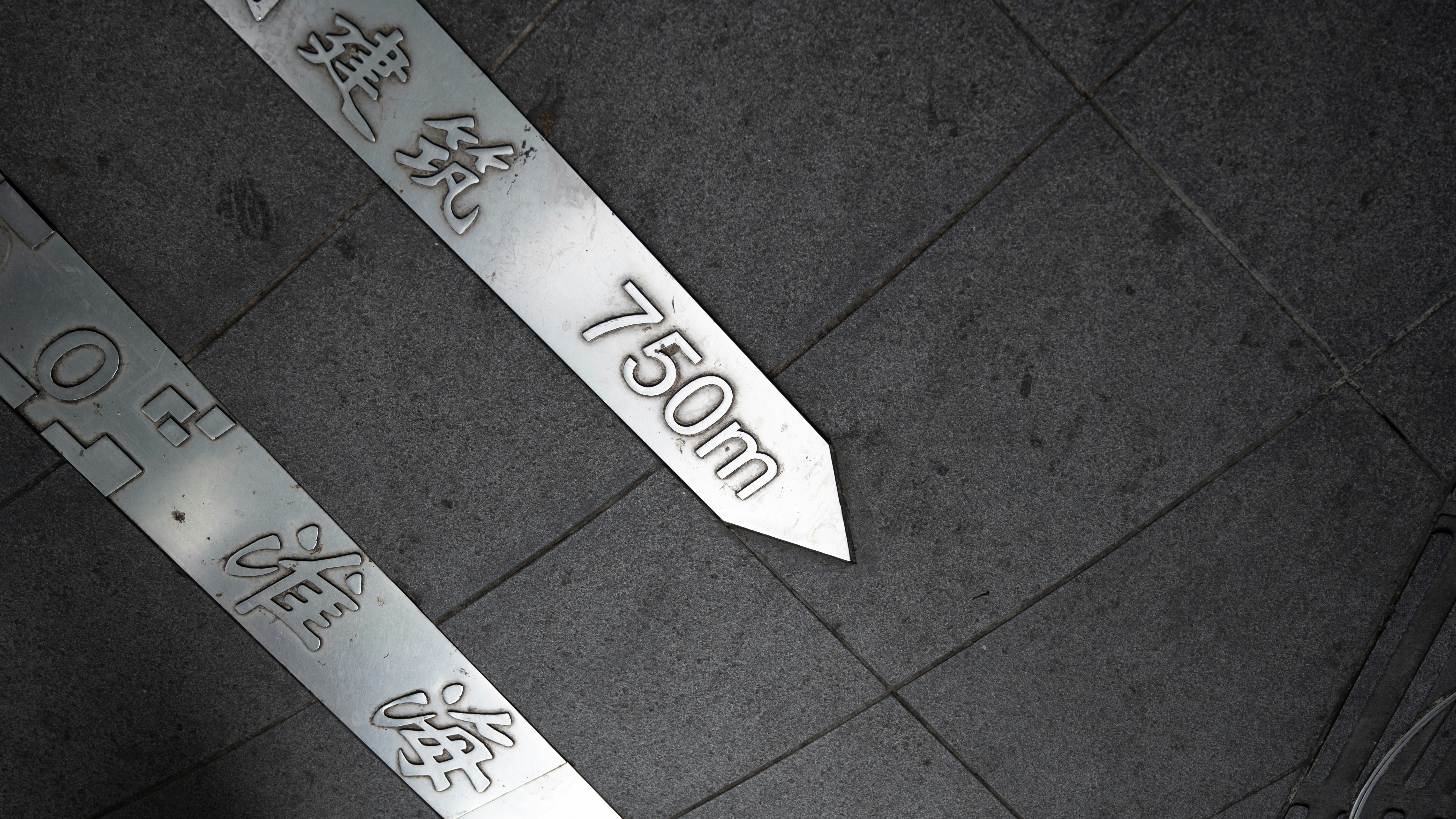 Metal marker shows 750m on a tiled surface.