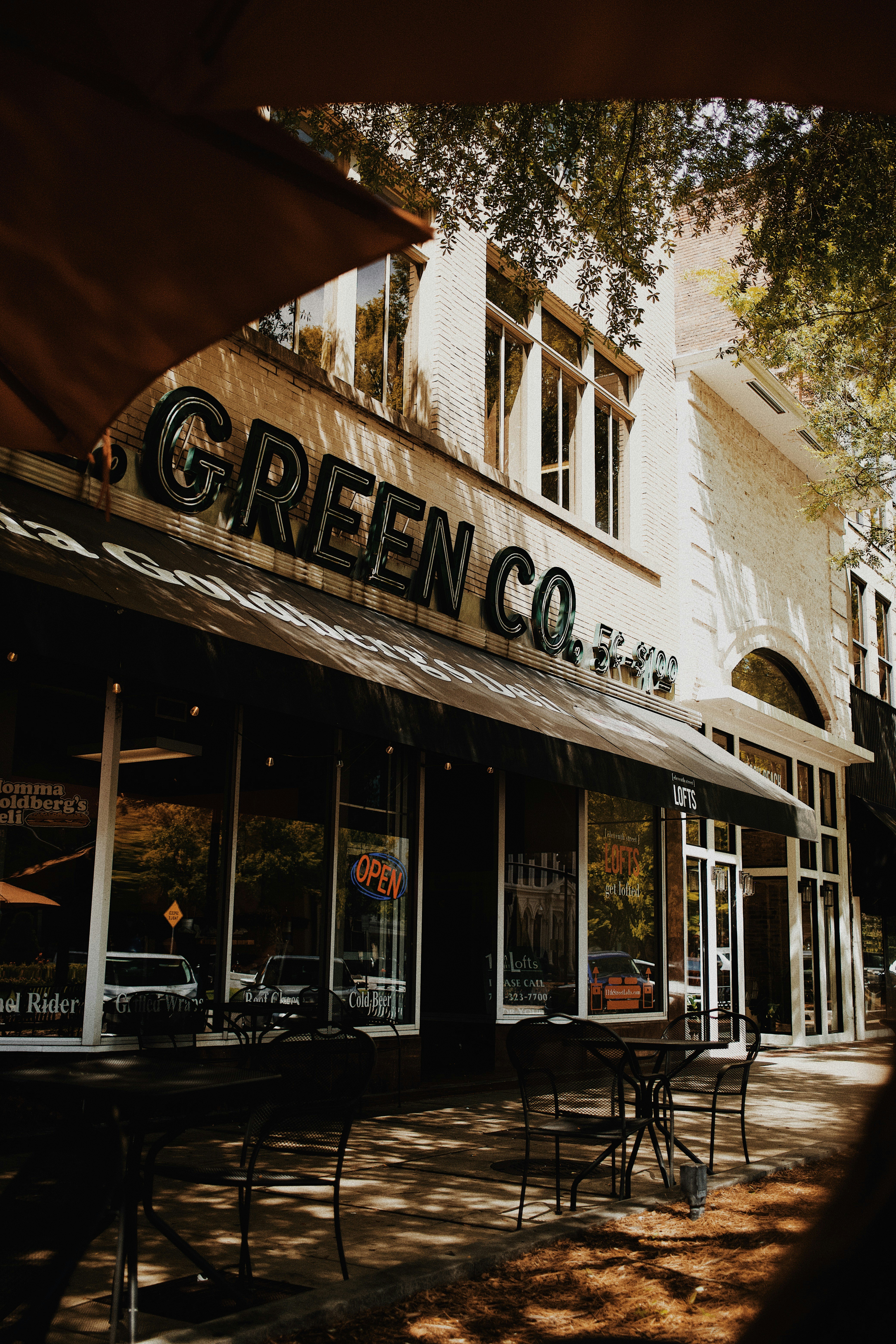 Green co. storefront with outdoor seating and awning.