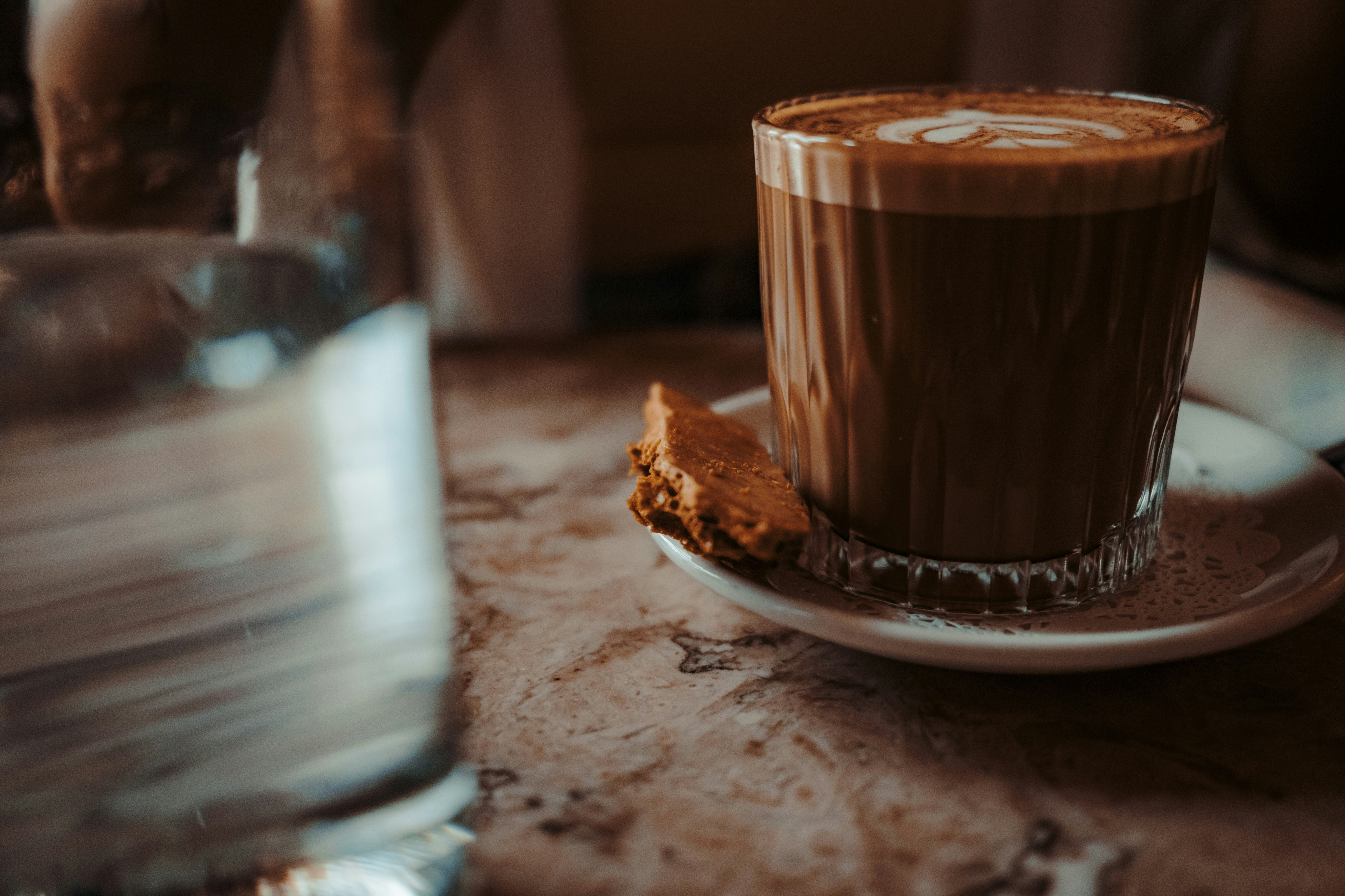A glass of coffee with latte art and a cookie