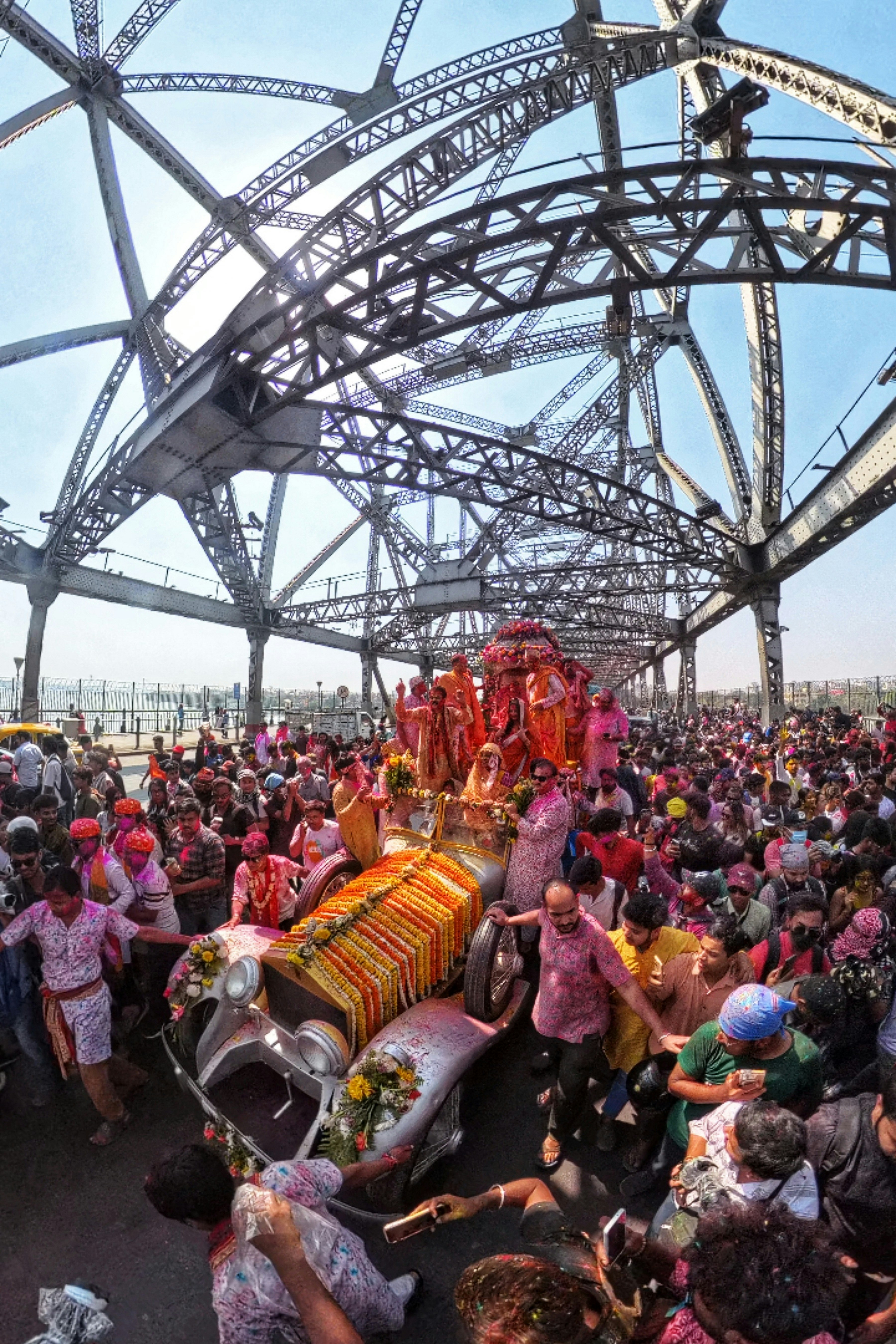 Wedding procession on a bridge with a decorated car.