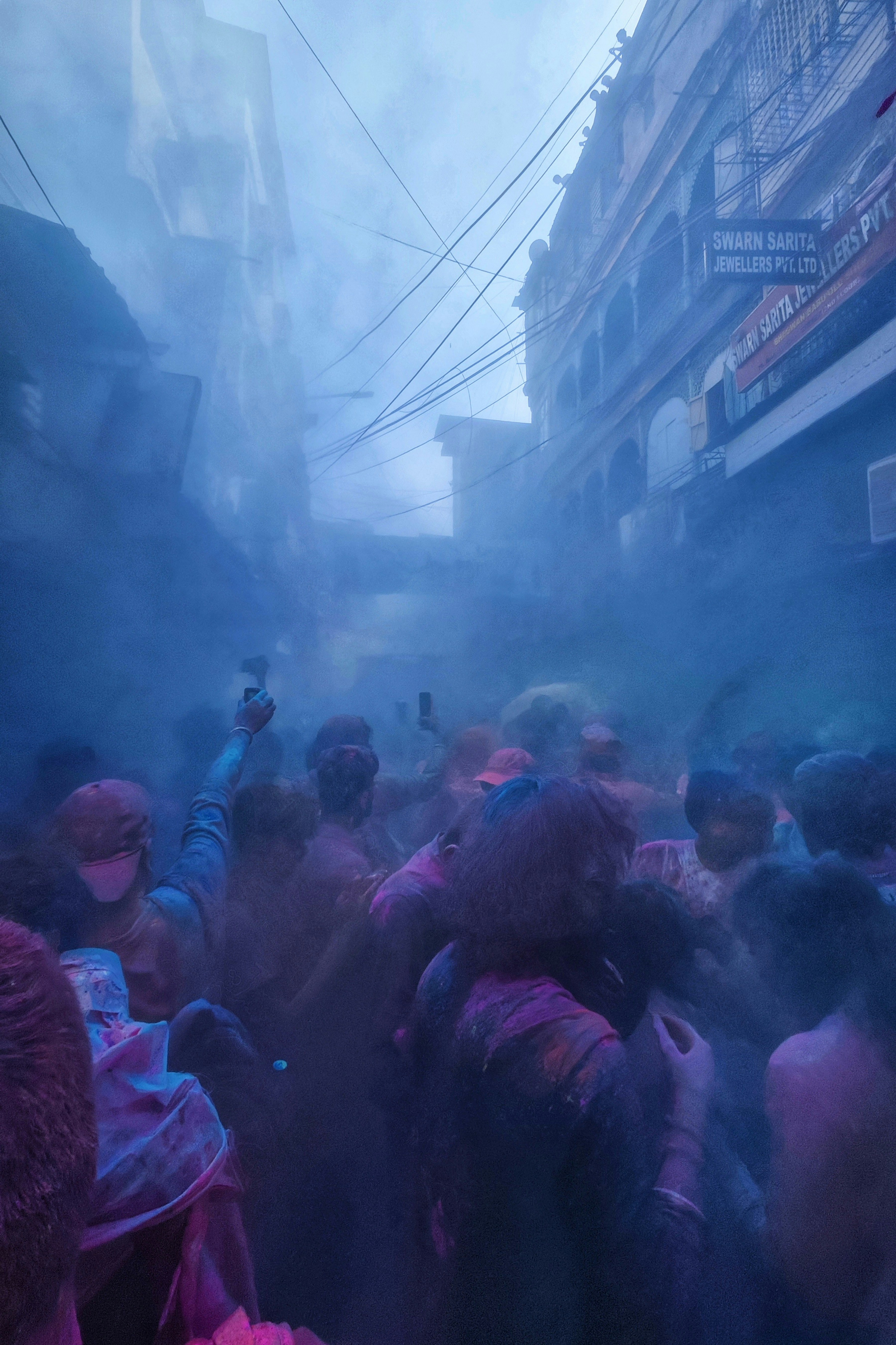 A street engulfed in blue powder as a crowd celebrates Holi in India