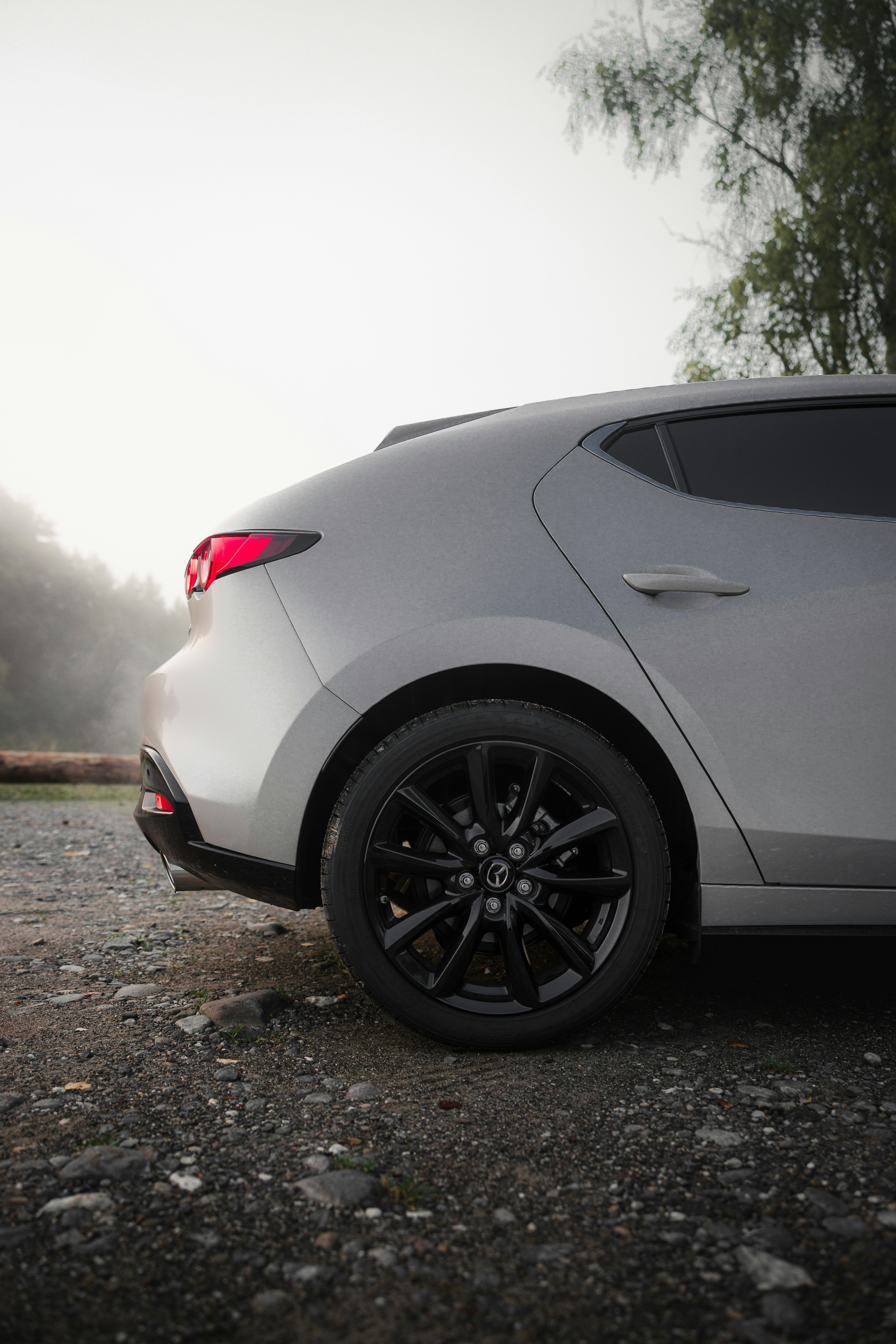 Silver car with black wheels on gravel road