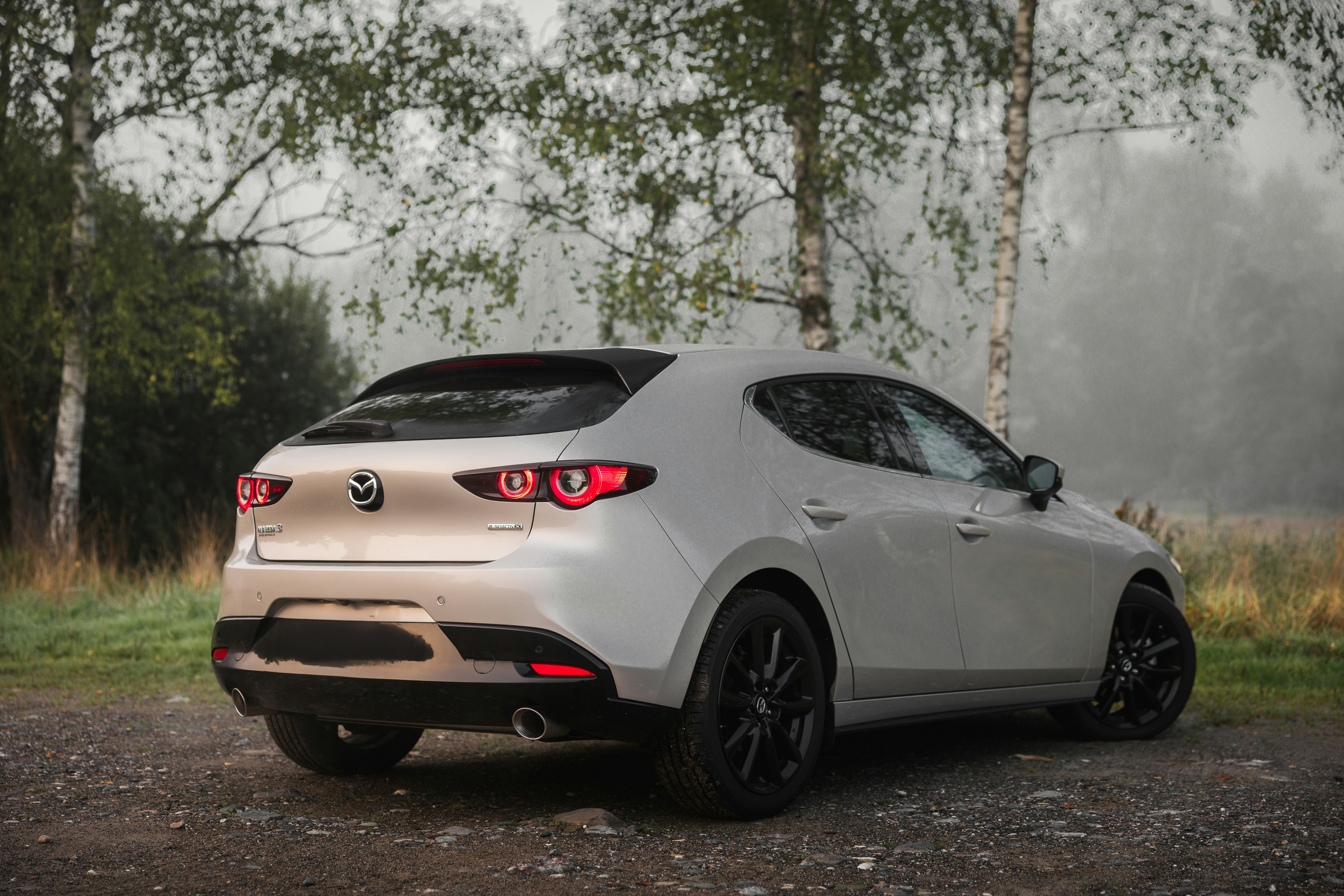 White hatchback car parked on a dirt road.