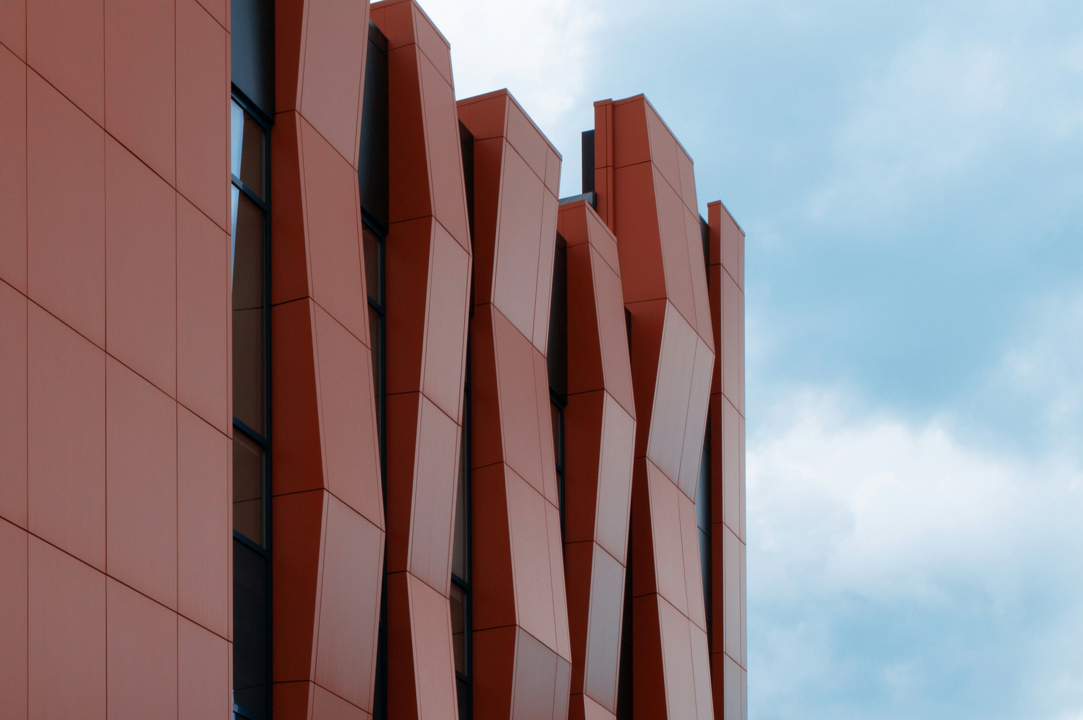 幾何学的な赤いパネルを備えたモダンな建物のファサード。