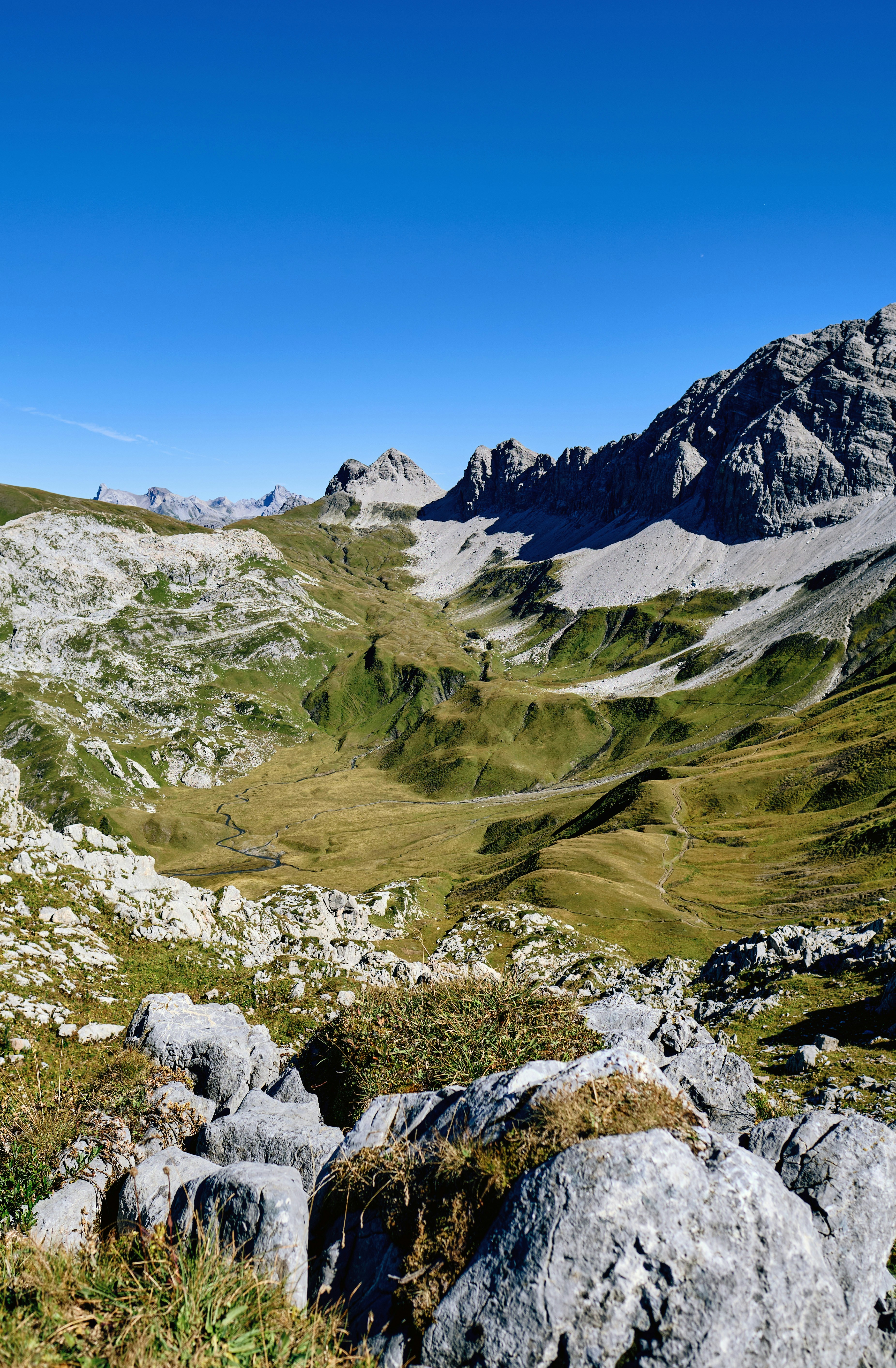 Rocky mountain valley with green grass and clear sky