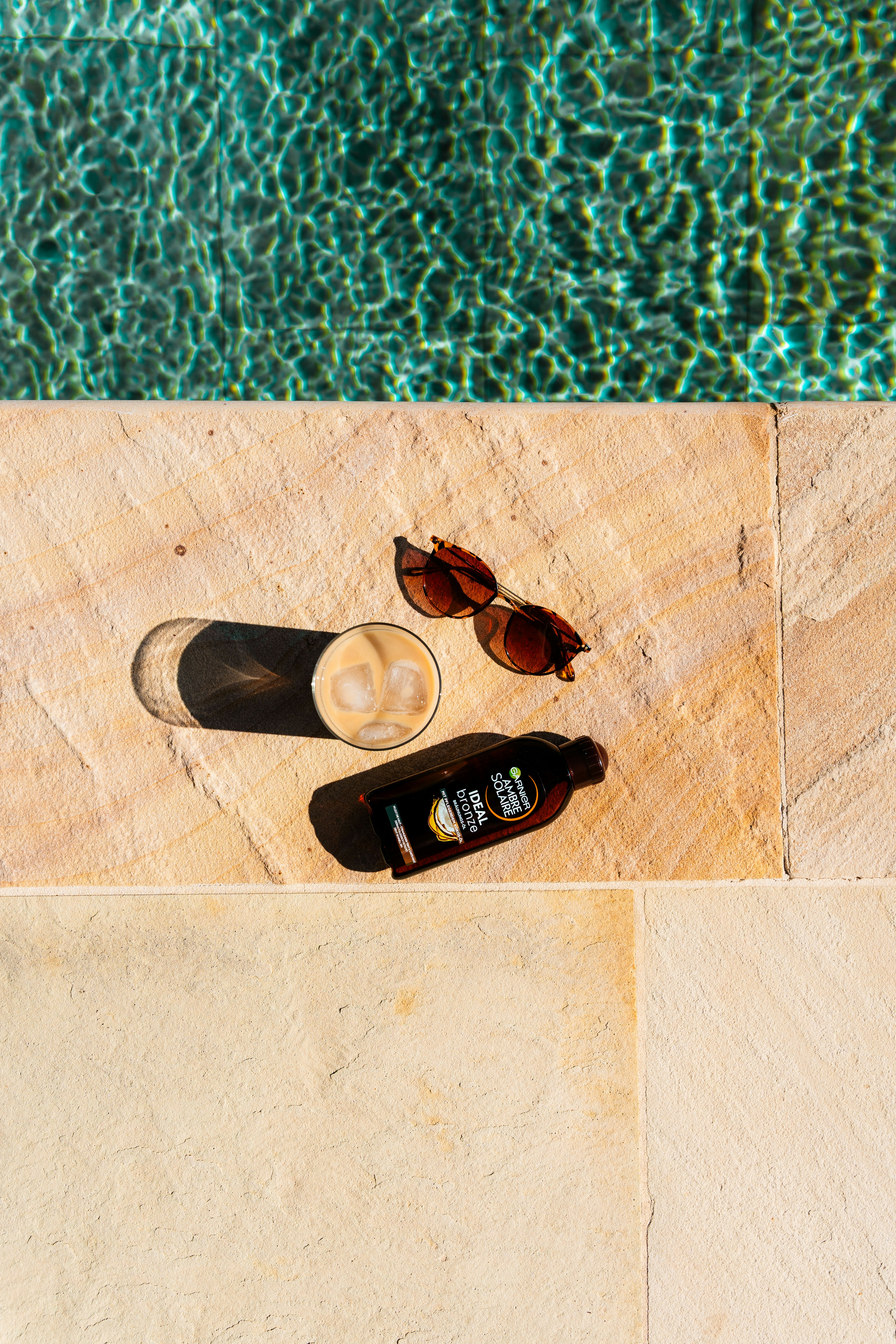 Iced coffee and sunglasses by the pool