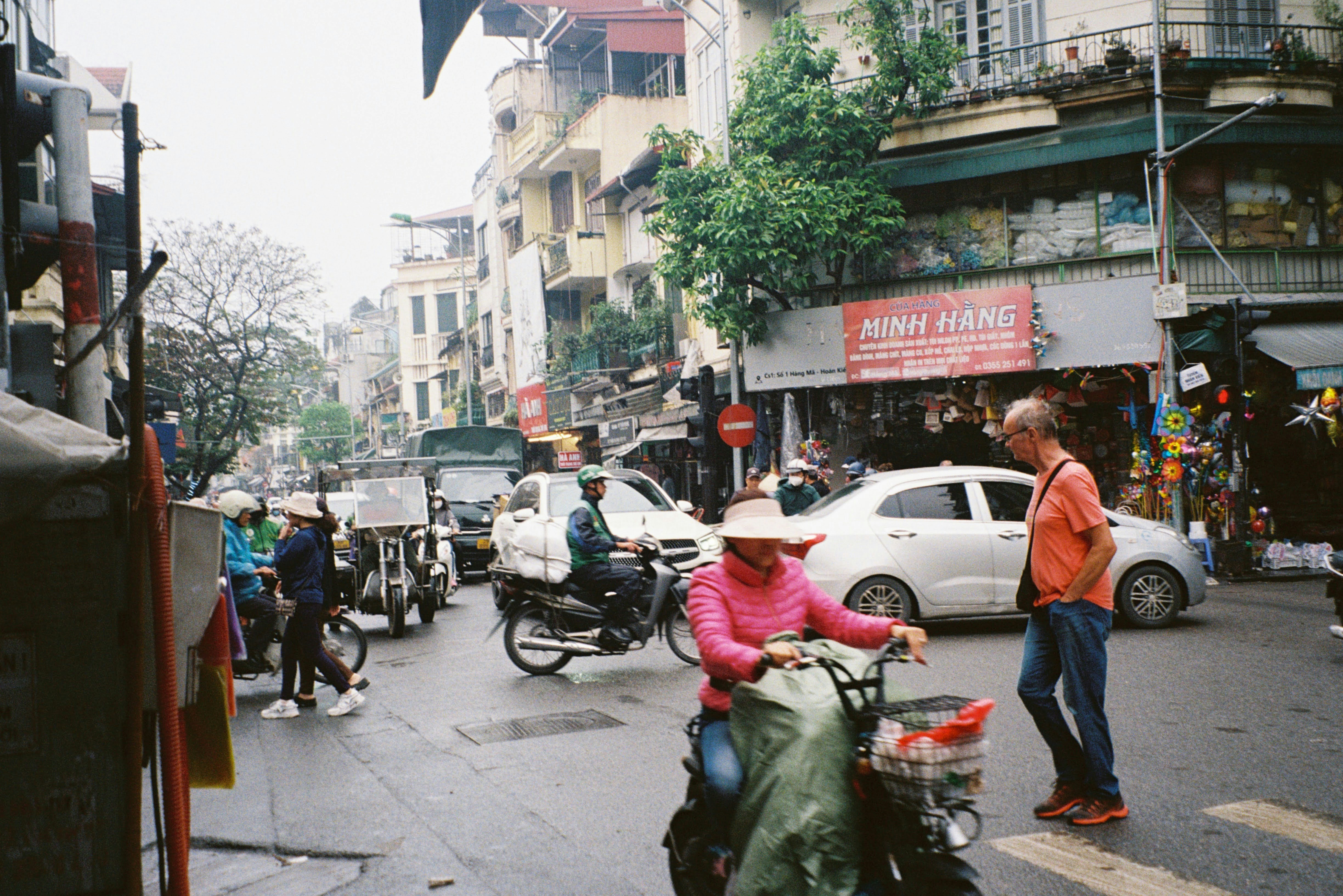 Busy street scene with people and vehicles in a city.
