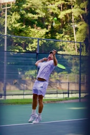 Man serving tennis ball on outdoor court