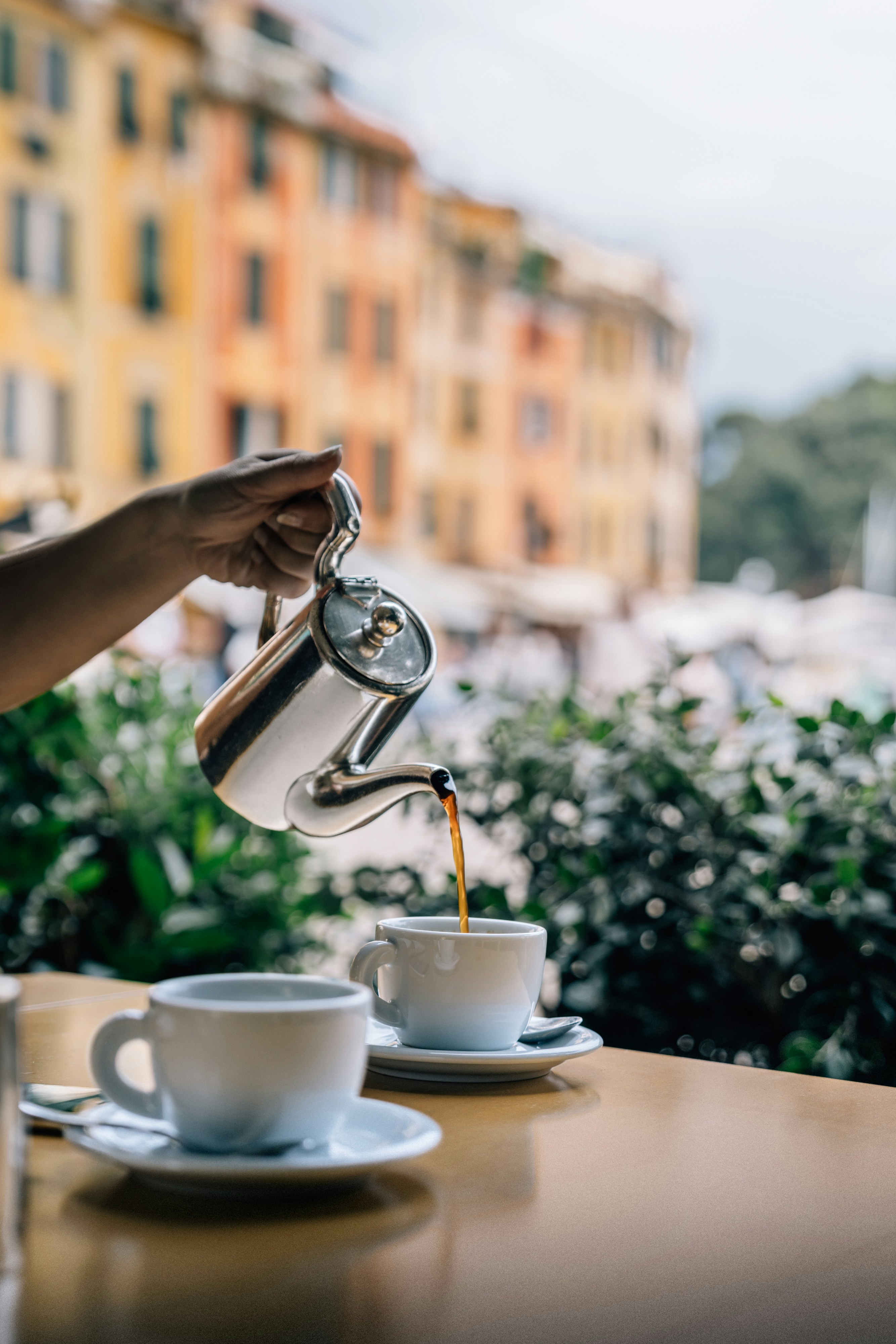 Pouring coffee into a cup at an outdoor cafe.
