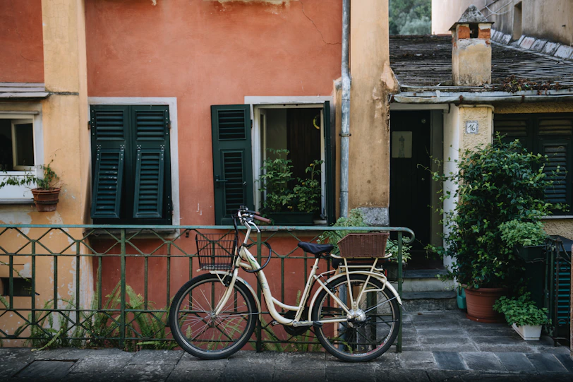 A bicycle parked against a building with shutters.