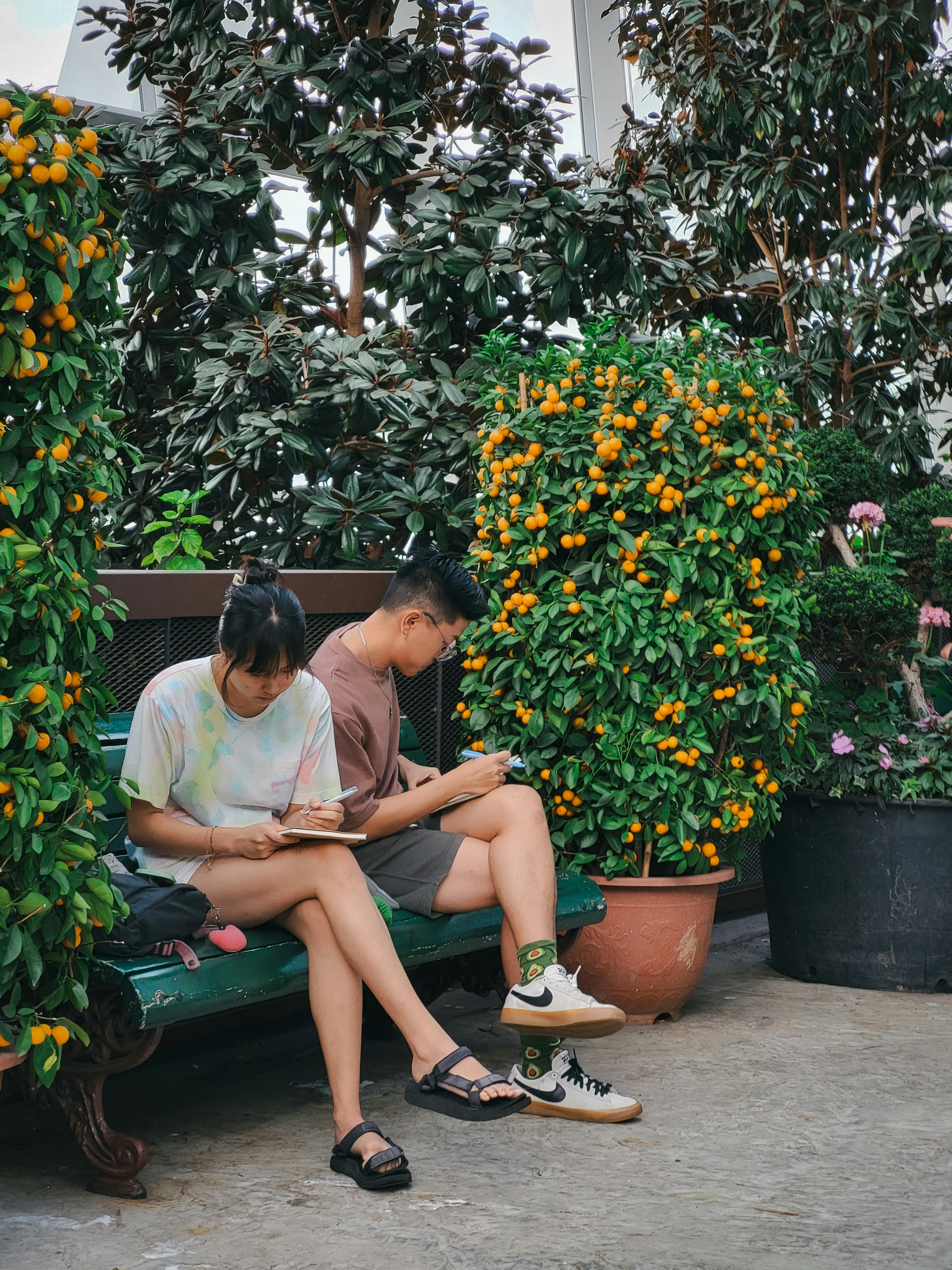 Two people sitting on a bench reading books.