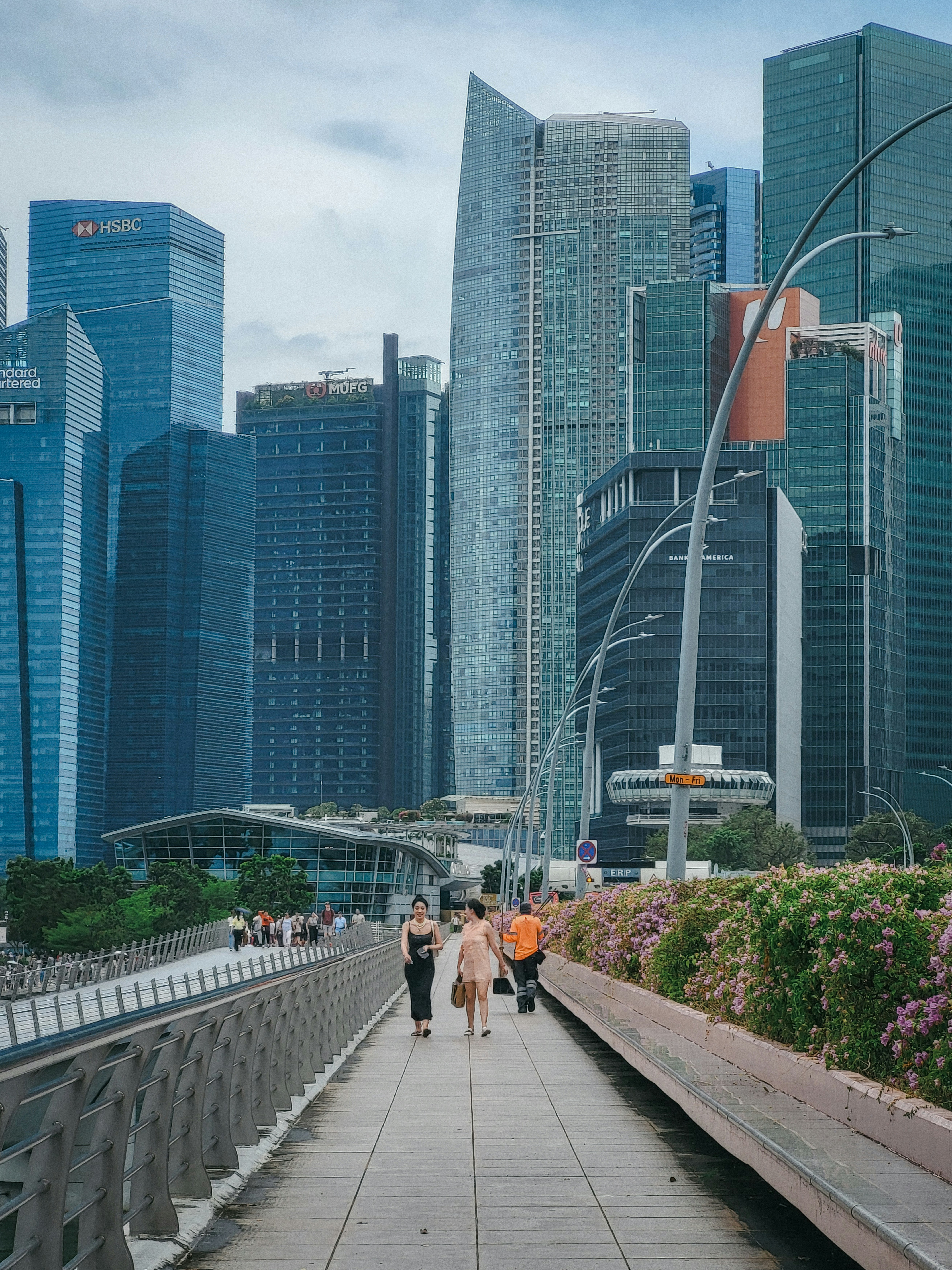 People walk on a bridge with city skyscrapers in background