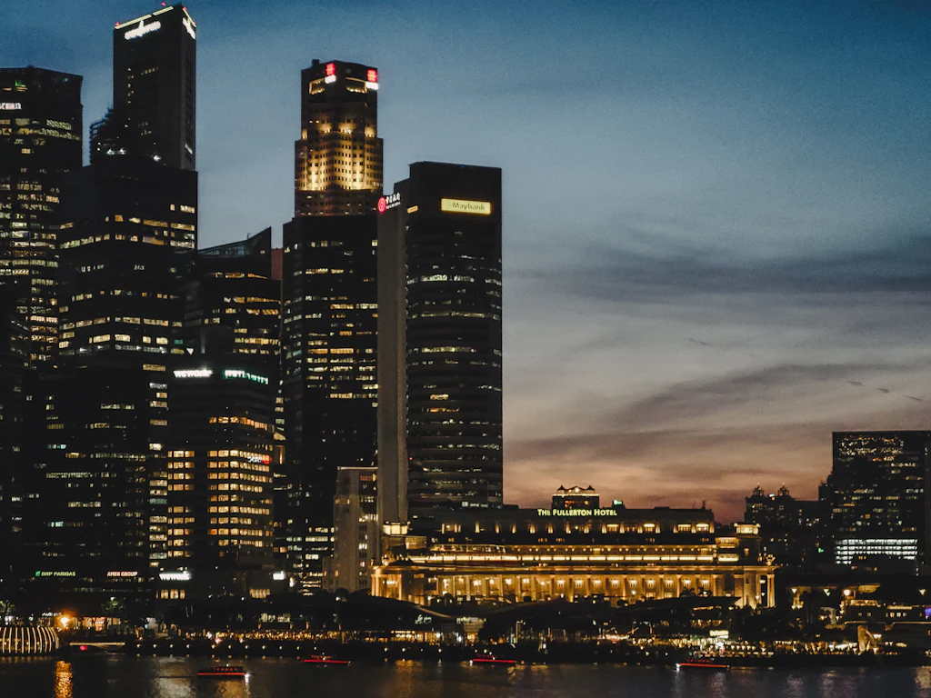 The Fullerton building and the Singapore central business district lit at dusk across the river