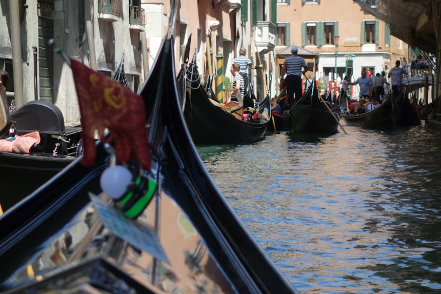 Gondolas and pastel palazzi along a Venetian canal, a must-see when visiting Italy in summer