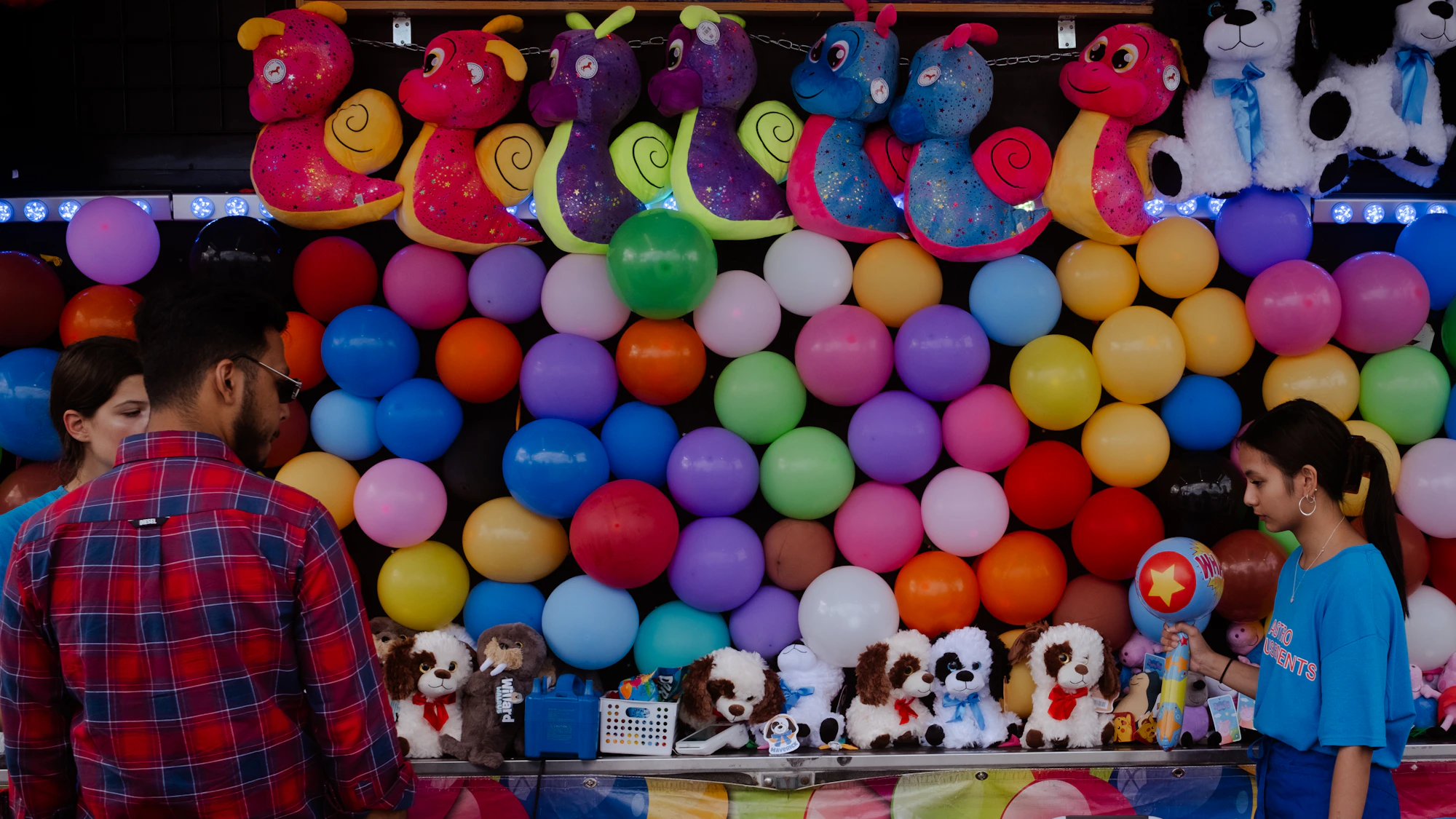 Kids playing a colorful balloon pop carnival game at a school carnival