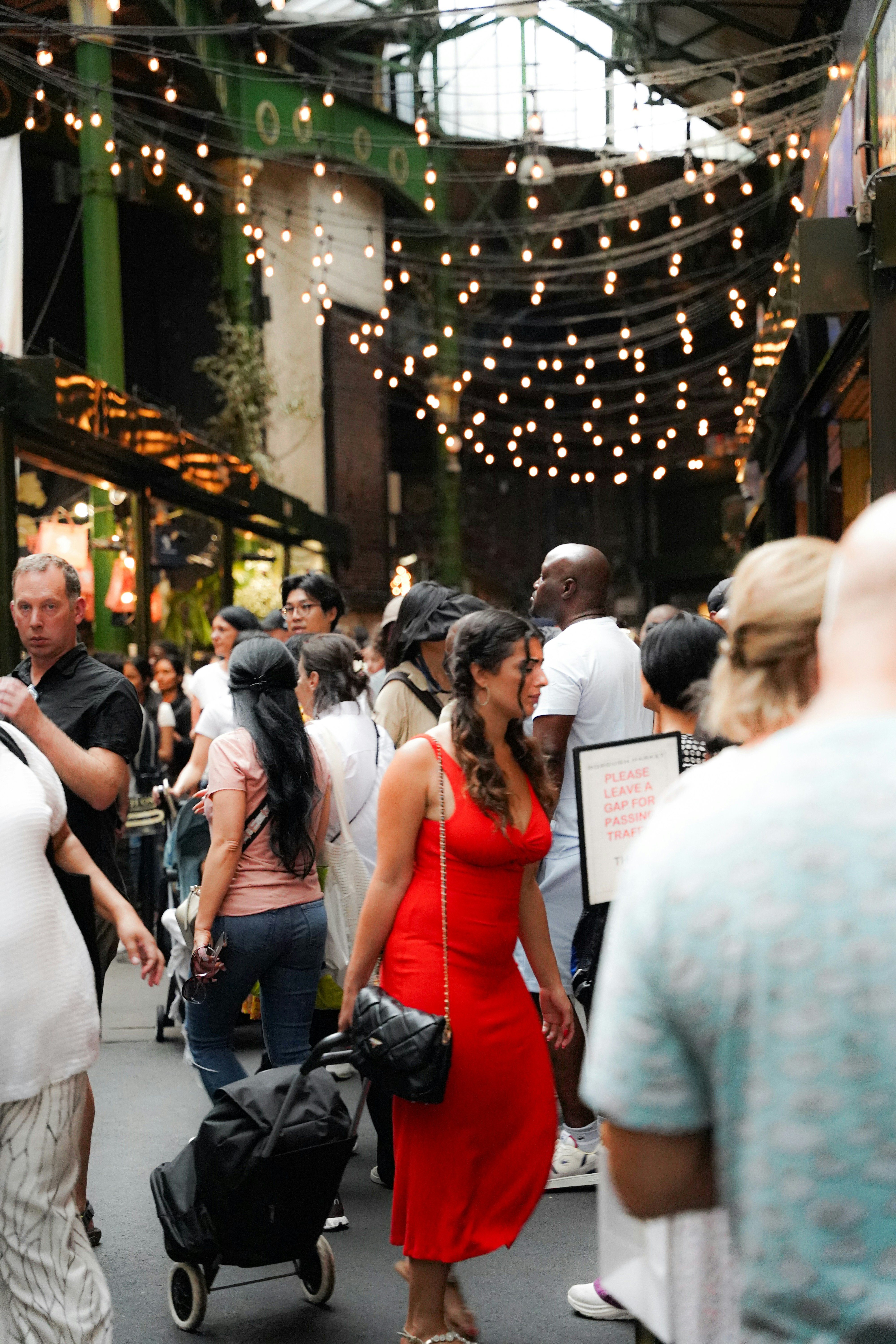 A woman in a red dress walks through a bustling market.