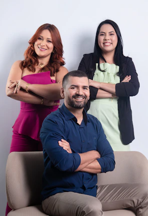 Three smiling people posing in front of a white background