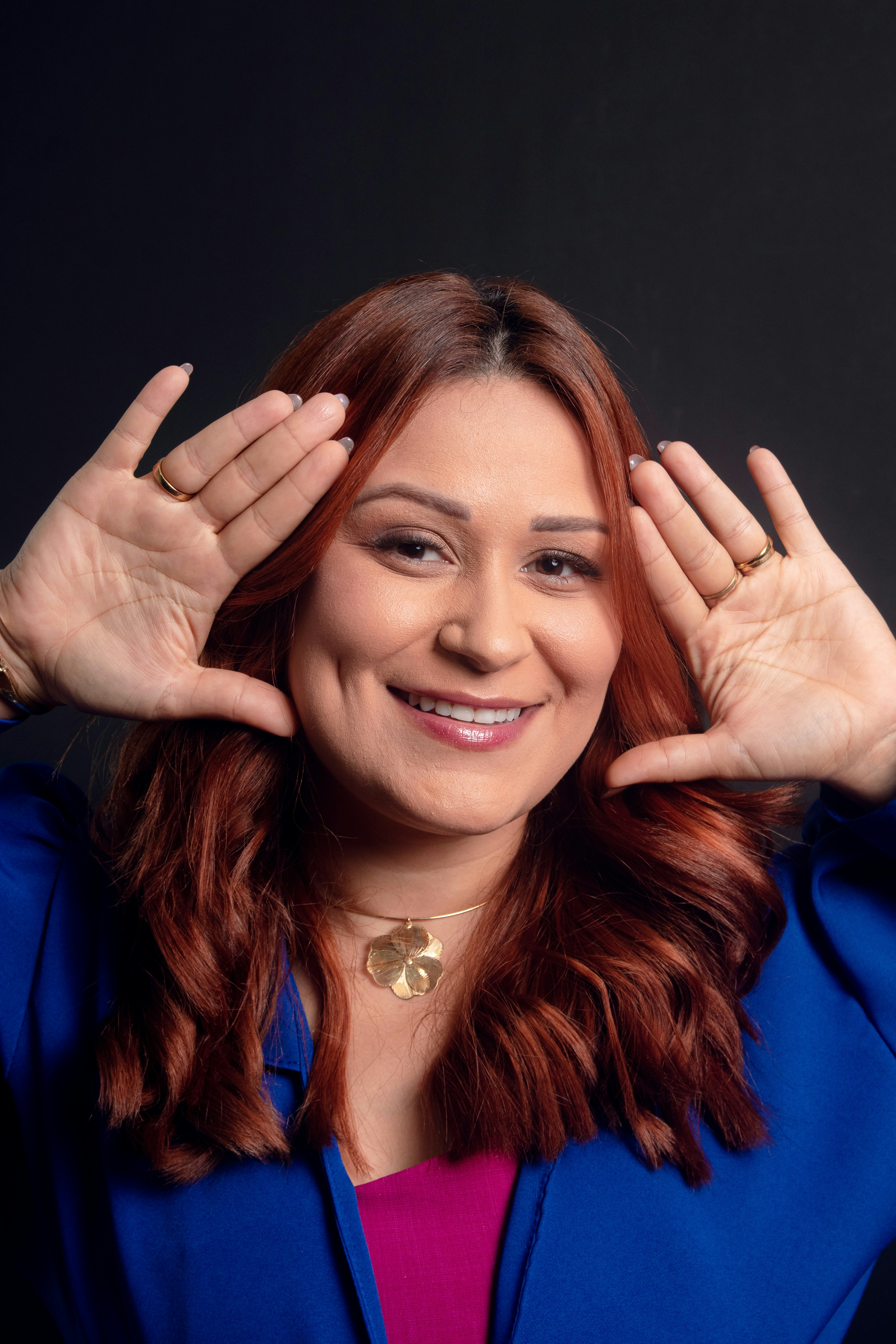 Wanita dengan rambut merah membingkai wajahnya dengan tangan.
