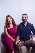 A smiling couple sits together on a modern chair.