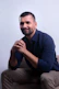Man sitting on a couch with hands clasped.
