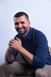 Man sitting on a chair, smiling at the camera.