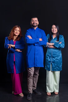 Three professionals in blue lab coats