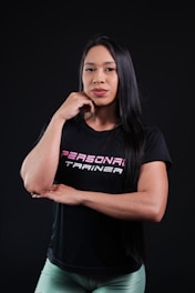 Woman wearing a personal trainer t-shirt on black background.