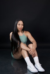 Woman with long dark hair sitting on floor.