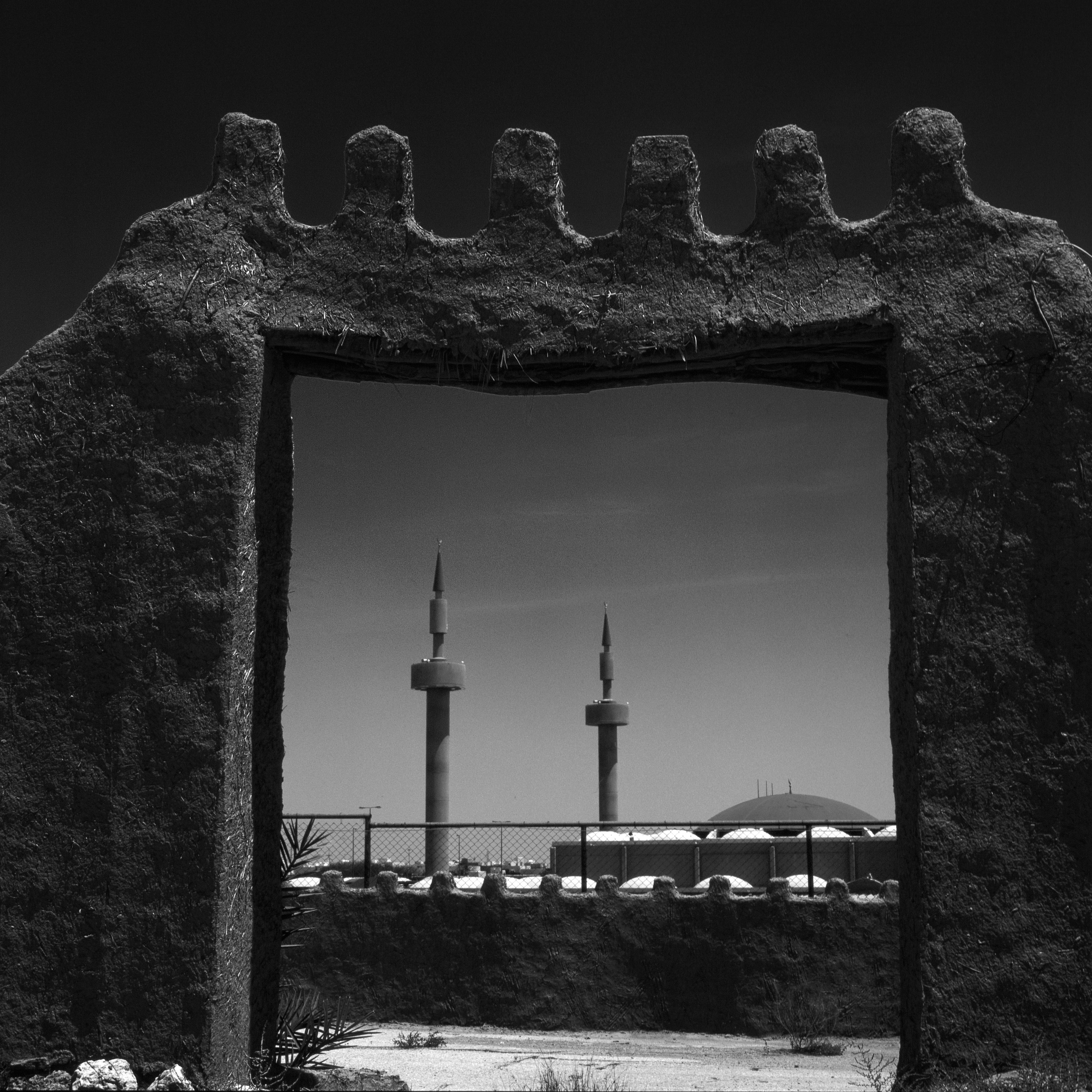 Stone archway framing mosque minarets and dome