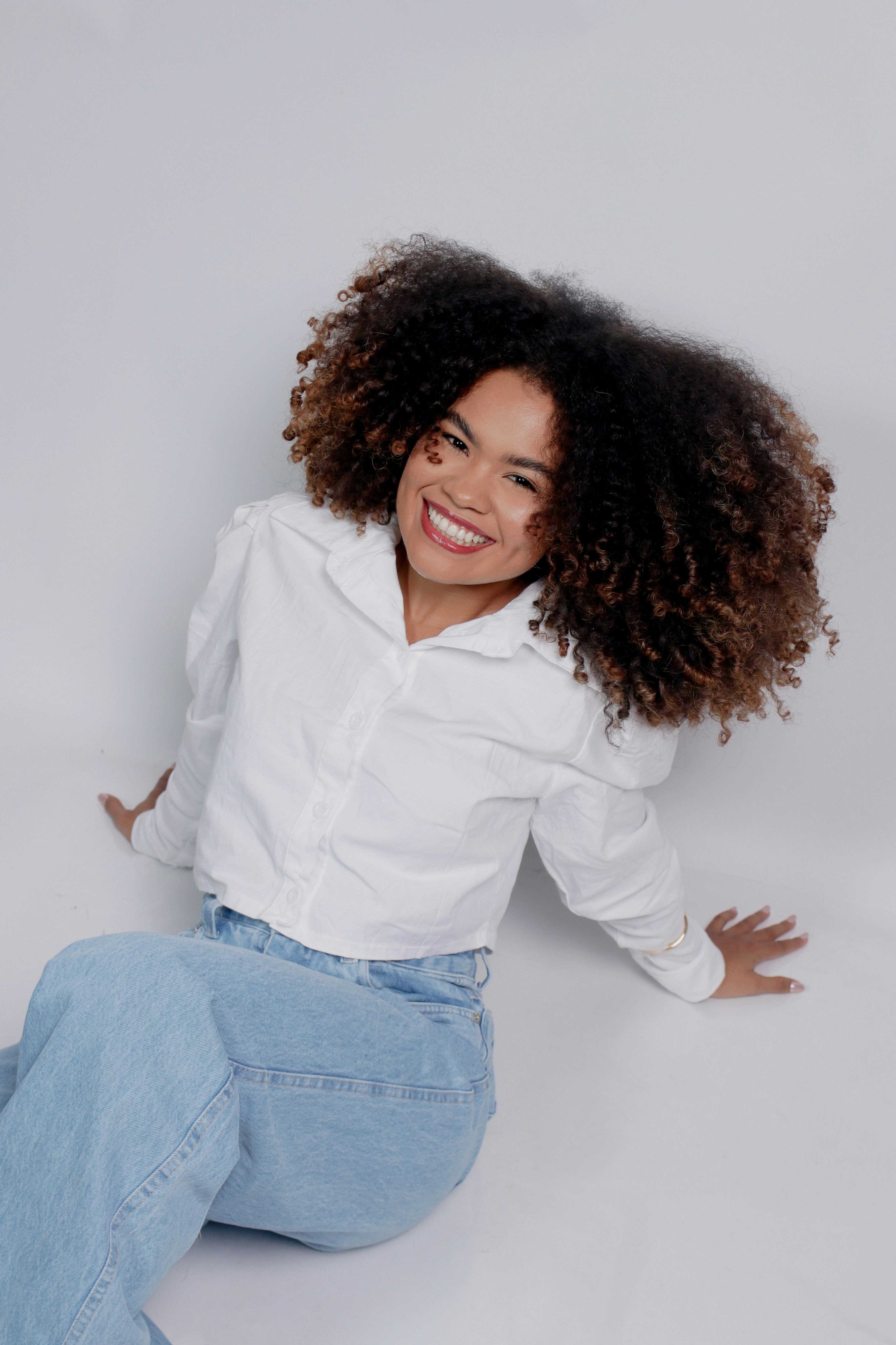 Smiling woman with curly hair in white shirt and jeans