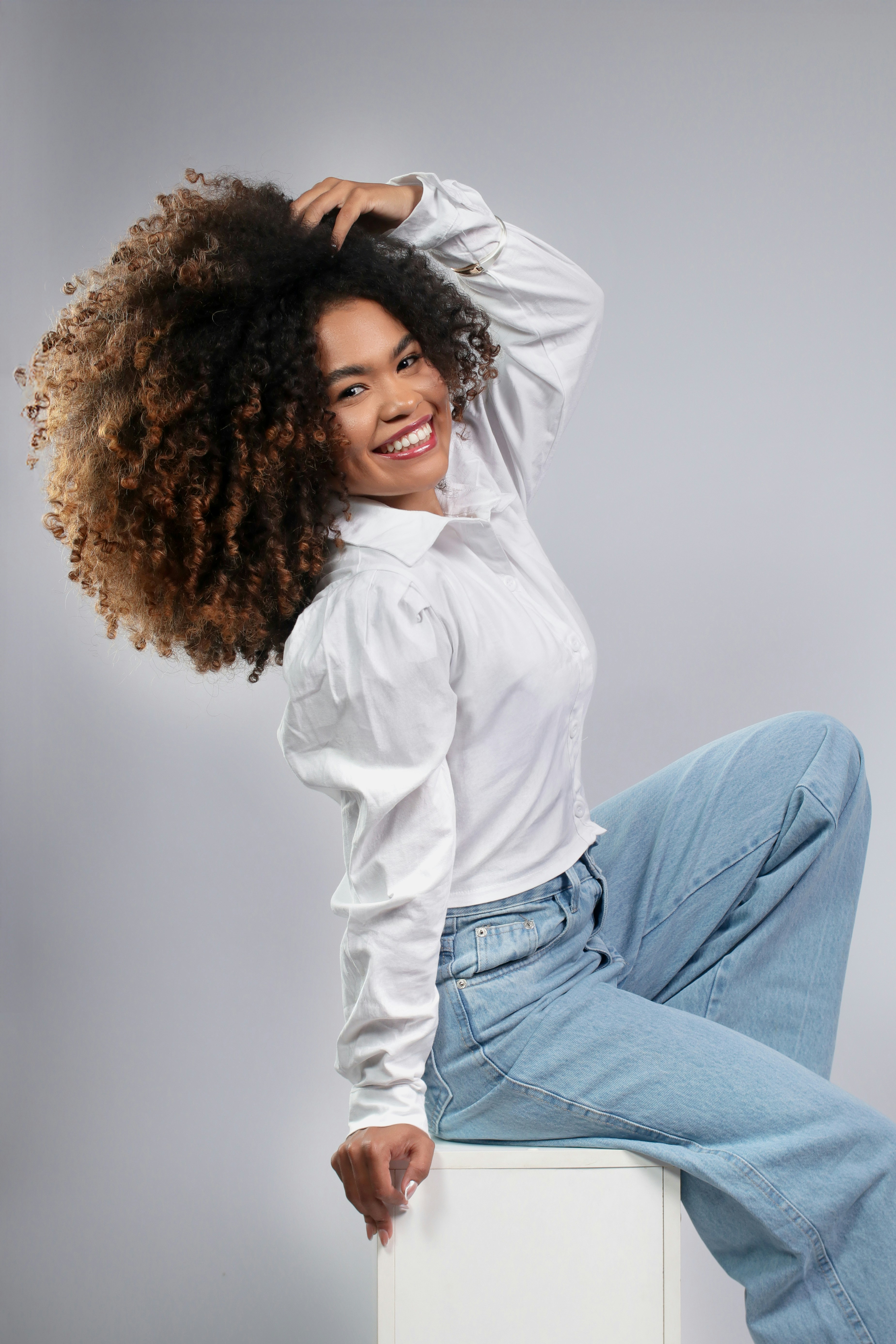 Woman with voluminous curly hair wearing a white shirt.