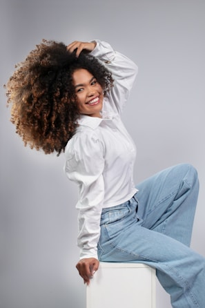 Woman with voluminous curly hair wearing a white shirt.
