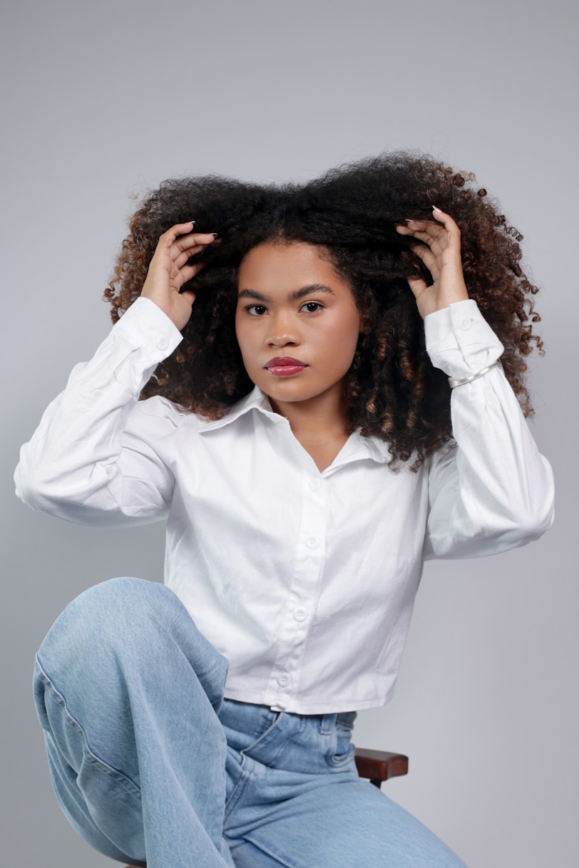 Woman with curly hair wearing a white shirt and jeans.