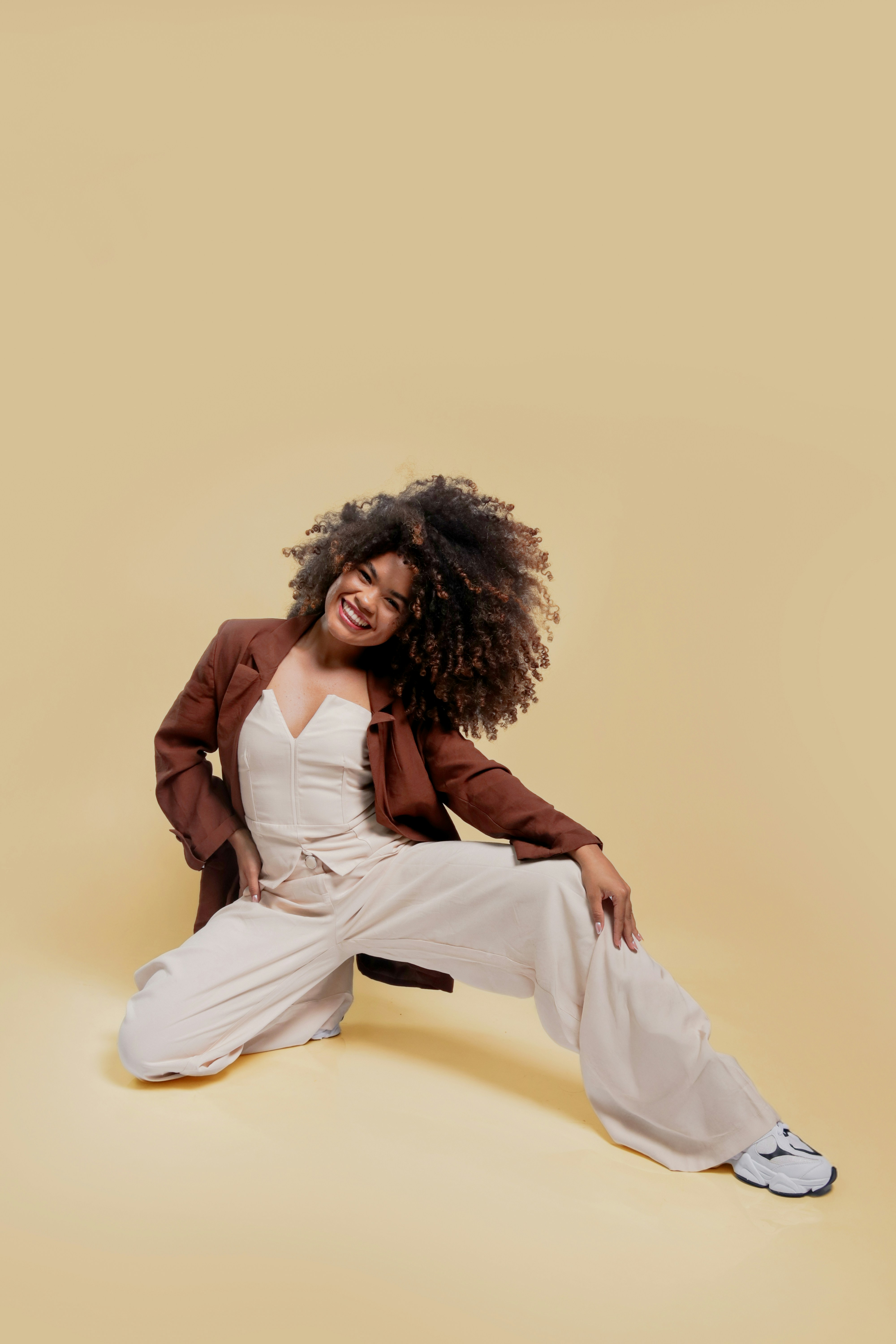 Young woman in stylish outfit posing on cream background