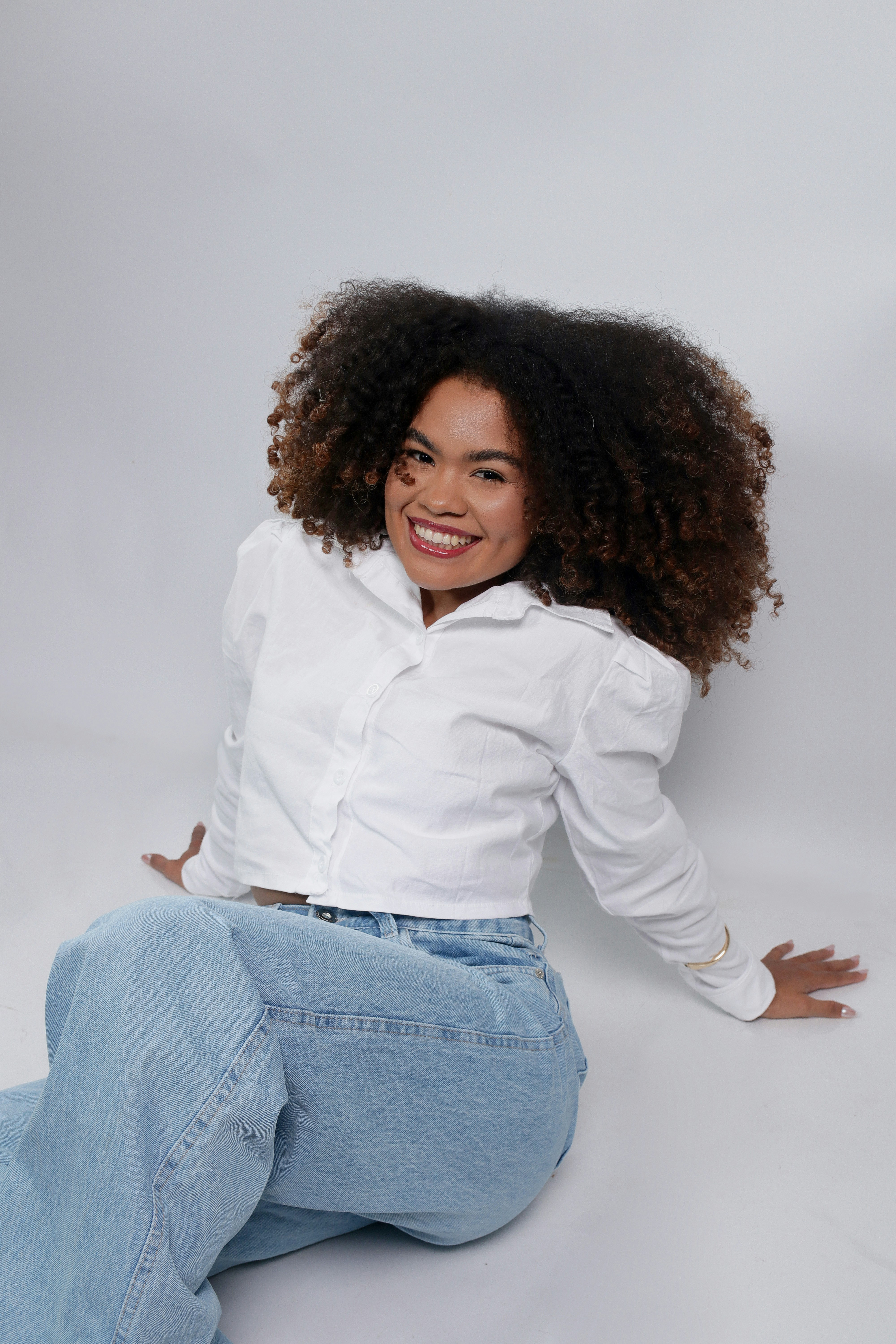 Smiling woman with curly hair wearing a white shirt.