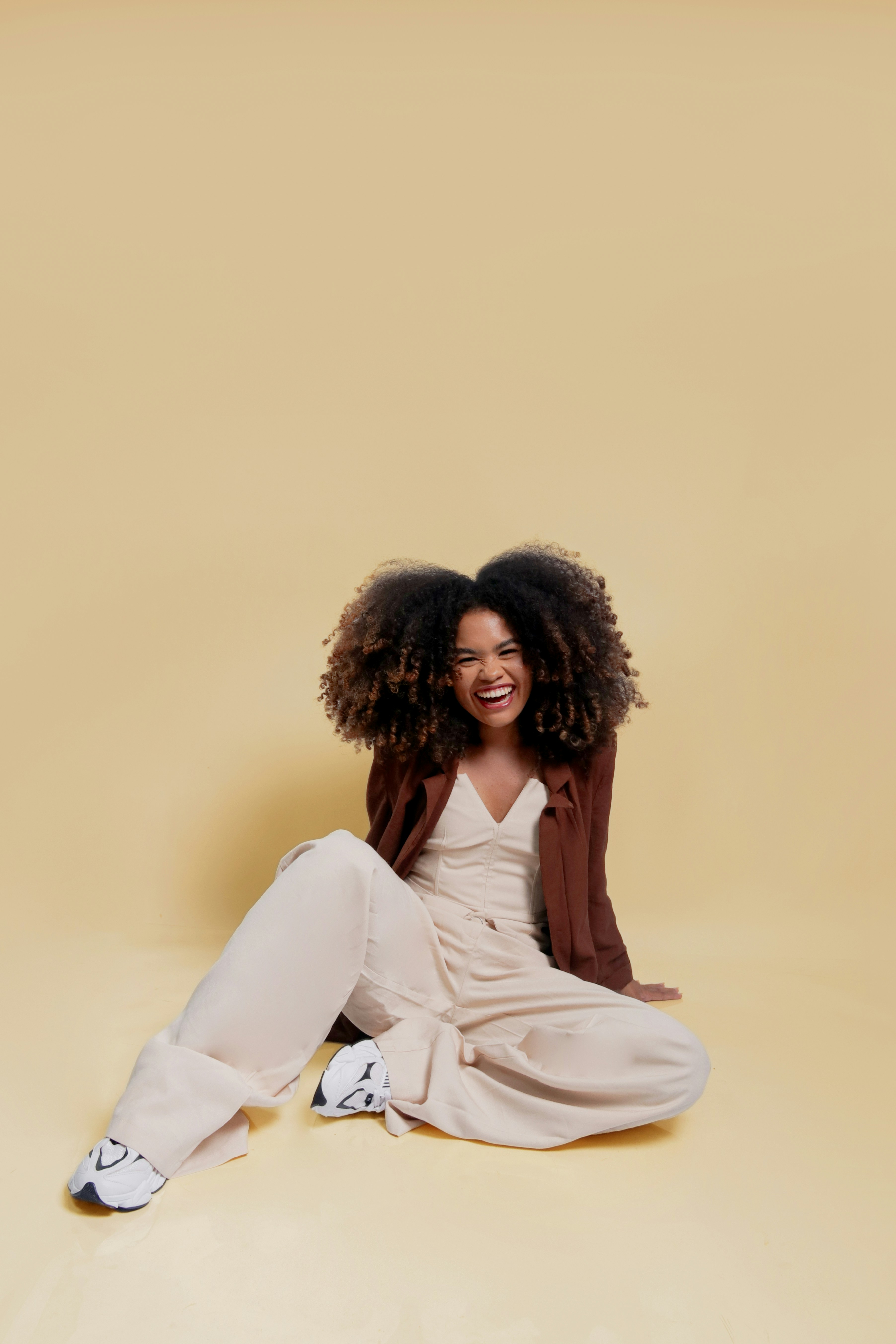 Woman with curly hair laughing on a yellow background