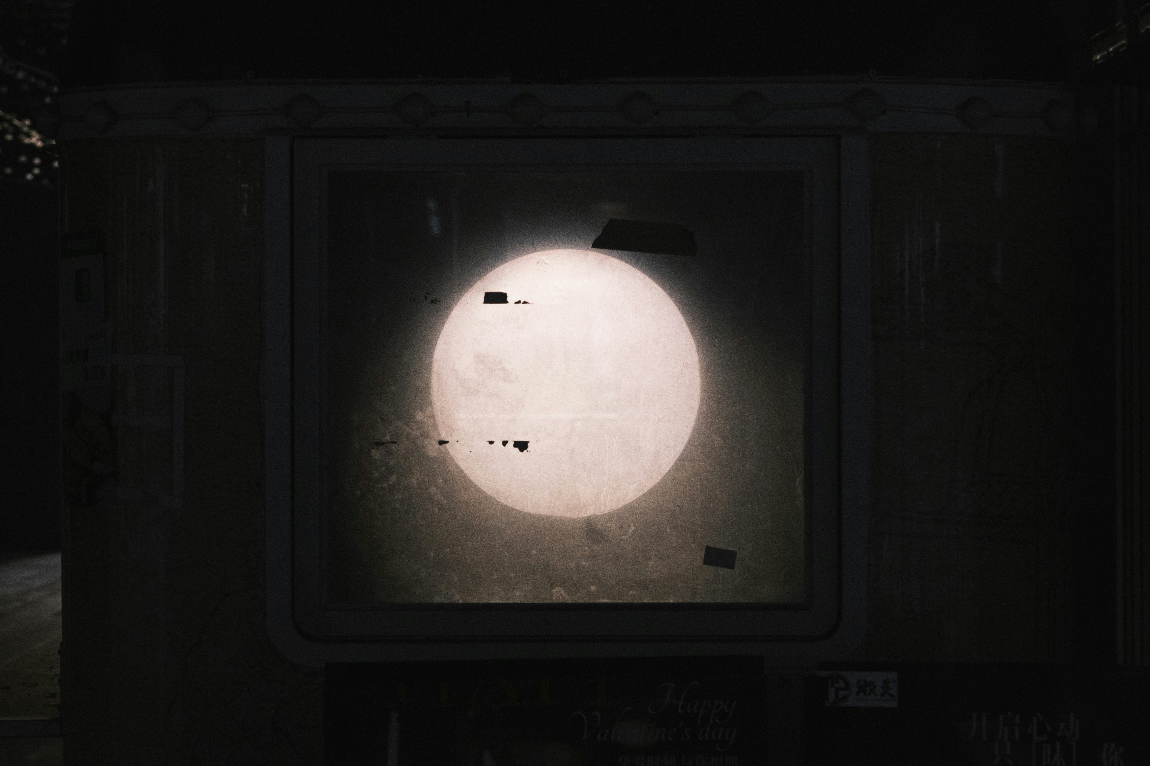 Full moon visible through a dirty window at night