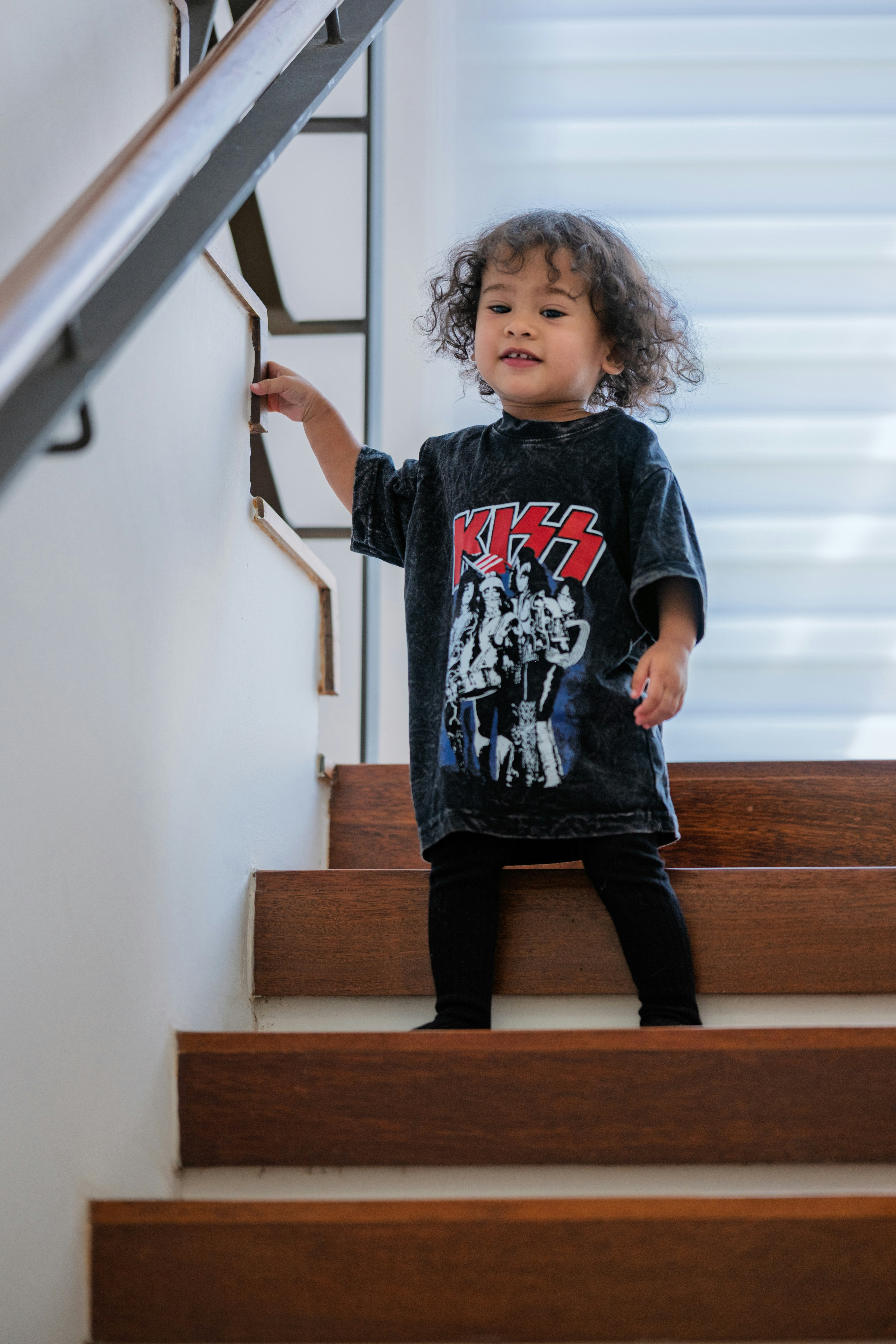 Young child in a band t-shirt on wooden stairs
