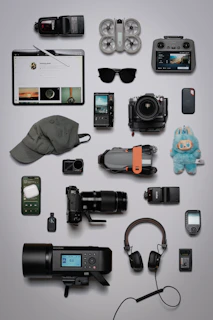 Flat lay of photography and tech gadgets on a grey background.