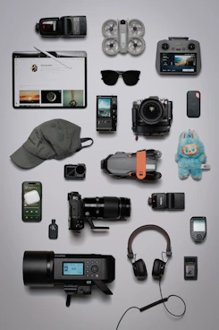 Flat lay of photography and tech gadgets on a grey background.