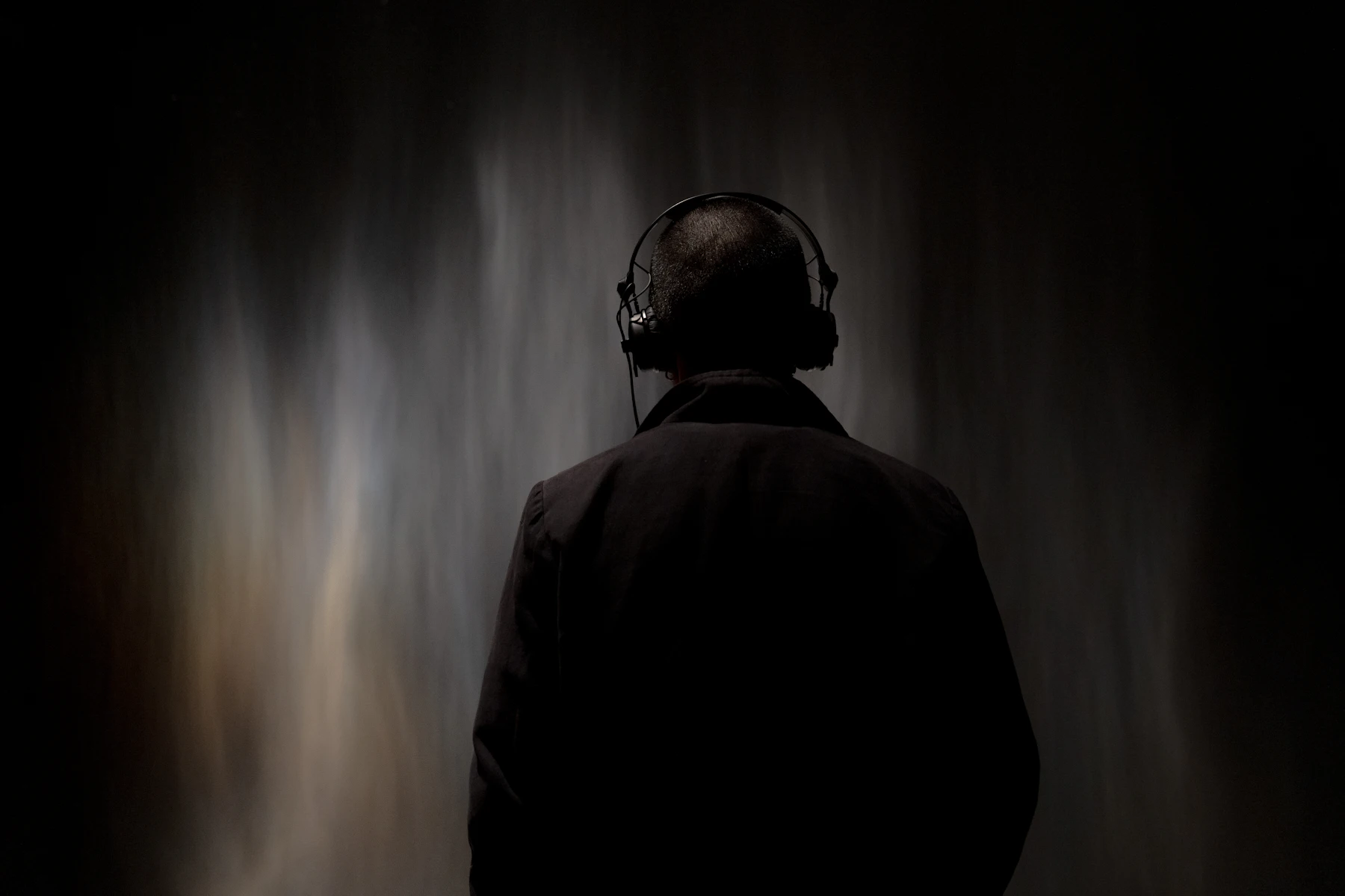 Person wearing over-ear headphones against a dark background